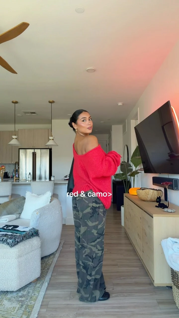 Red off-the-shoulder sweater with voluminous sleeves paired with green and black camo wide-leg pants.