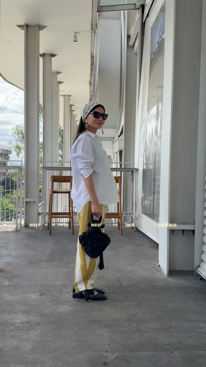 White button-up shirt with rolled sleeves paired with bold yellow striped wide-leg trousers and a gray headscarf.