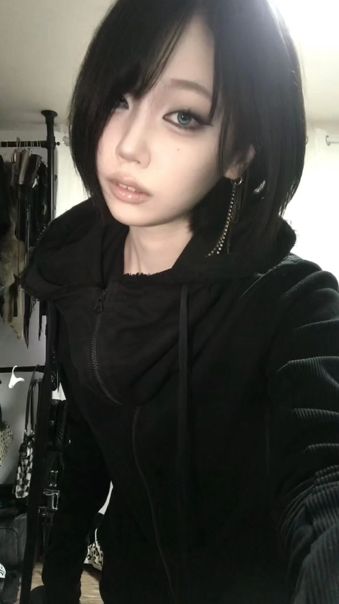 Close-fitting black hooded zip jacket with ribbed sleeves worn over a dark top.
