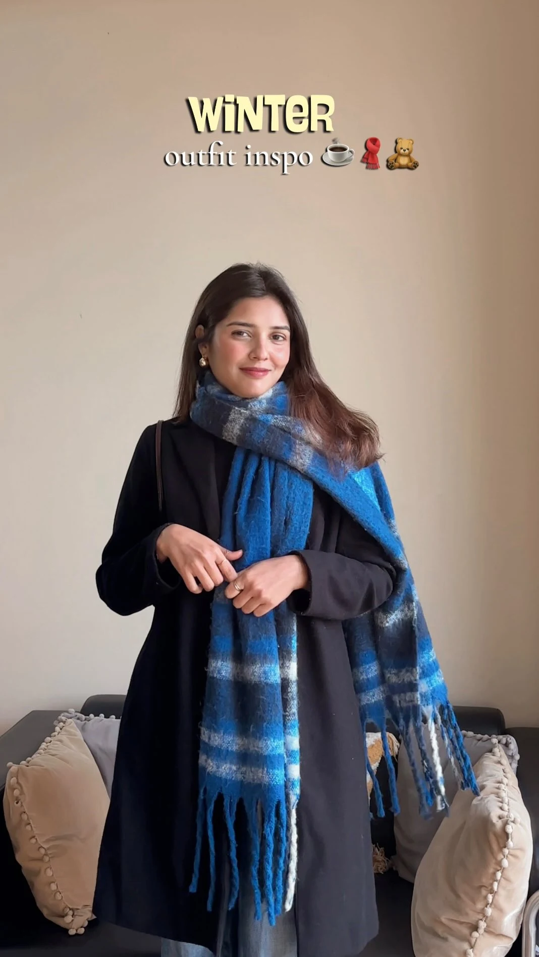 black long sleeve turtleneck, light blue wide leg jeans, long black longline coat, large blue and white plaid scarf
