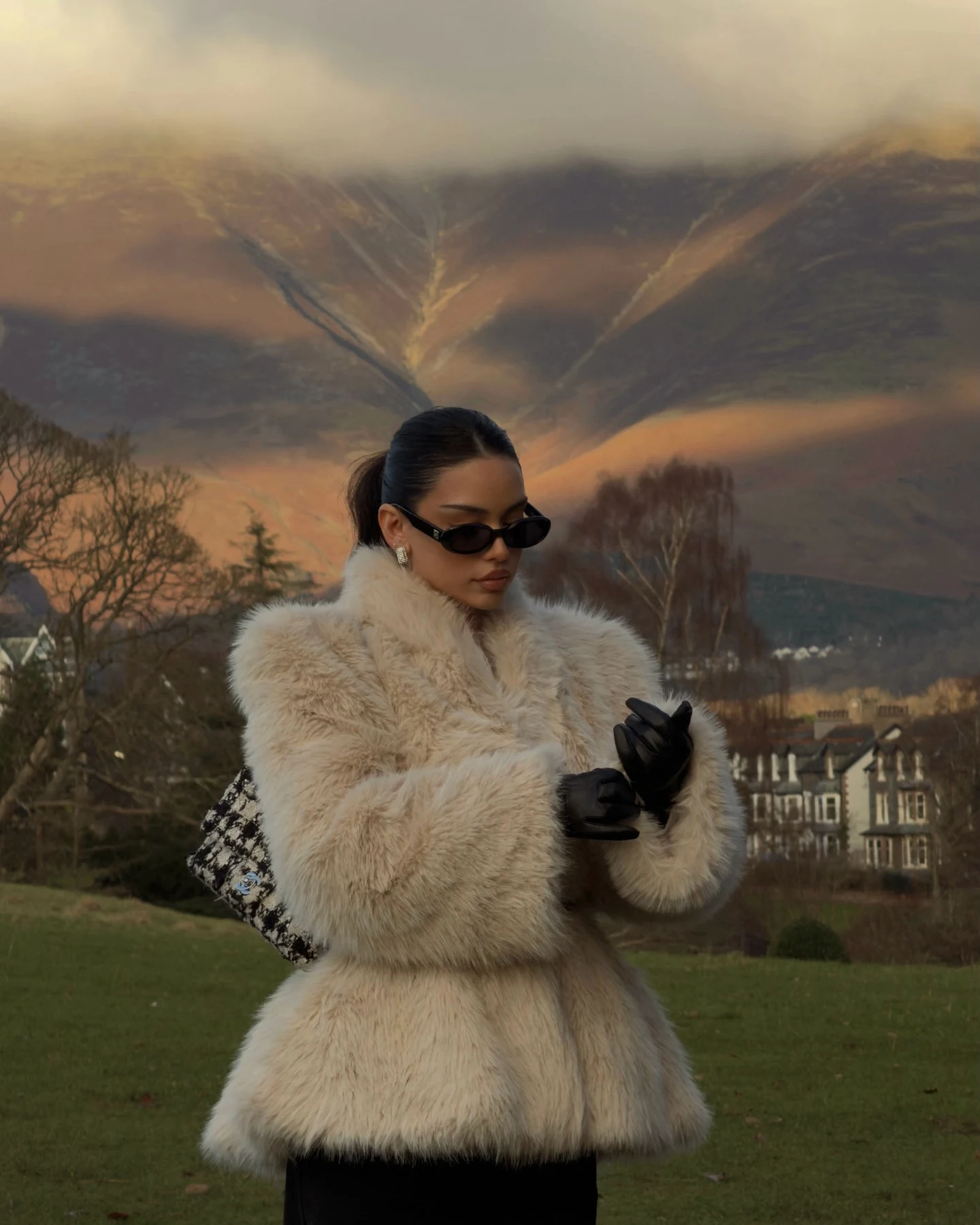 Woman in a cream teddy faux-fur coat, cream knit sweater, dark jeans, and brown hiking boots.