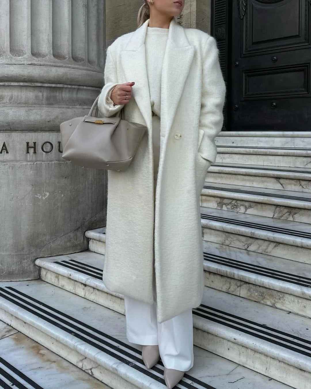 All-white outfit featuring a fluffy long coat, knit sweater, tailored trousers, and beige heels.
