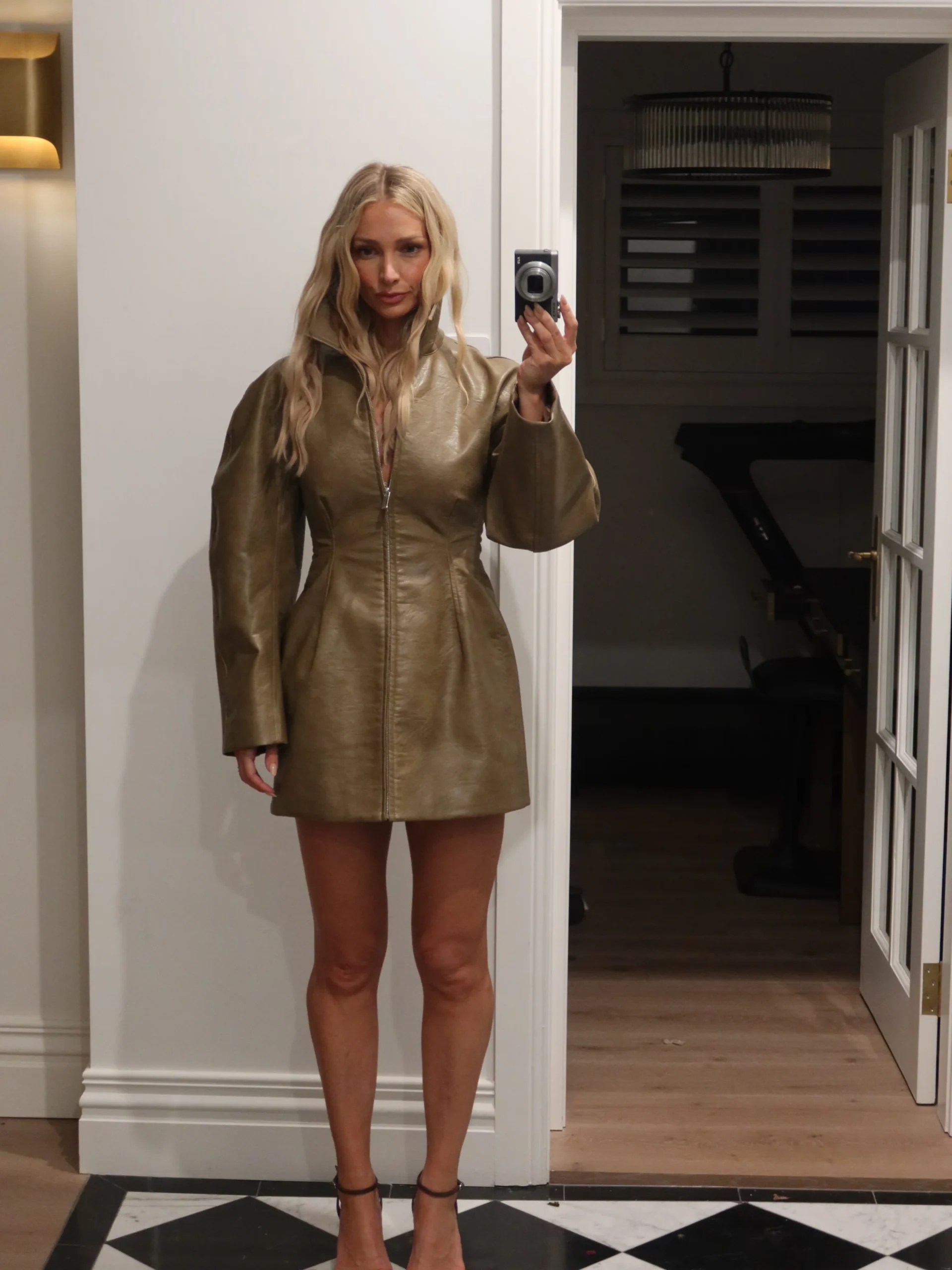 Olive green mini dress with flared skirt, front zipper, wide cuffs, and black ankle-strap heels.