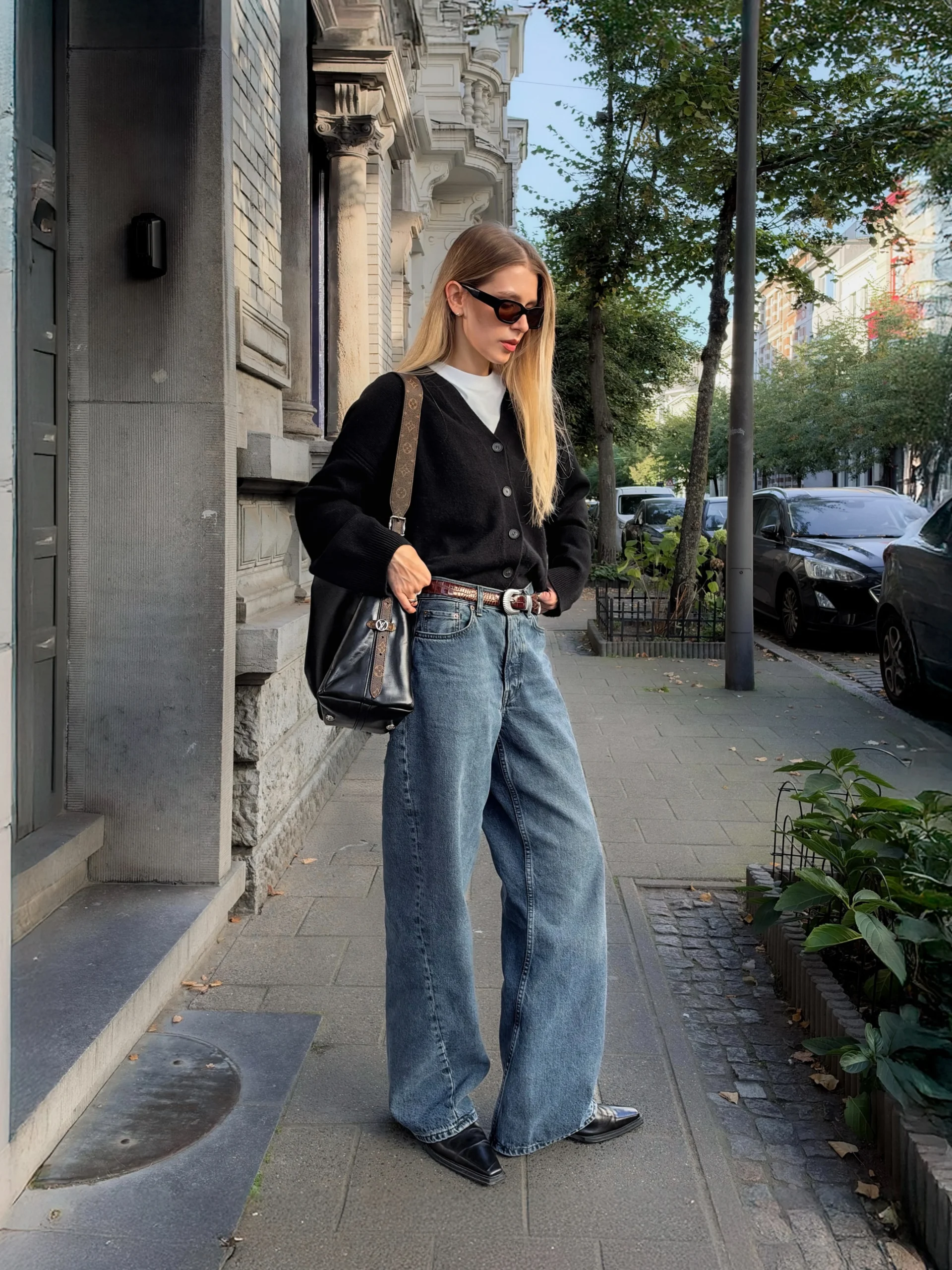 Oversized black knit cardigan over a white tee with high-waisted blue jeans and black boots.