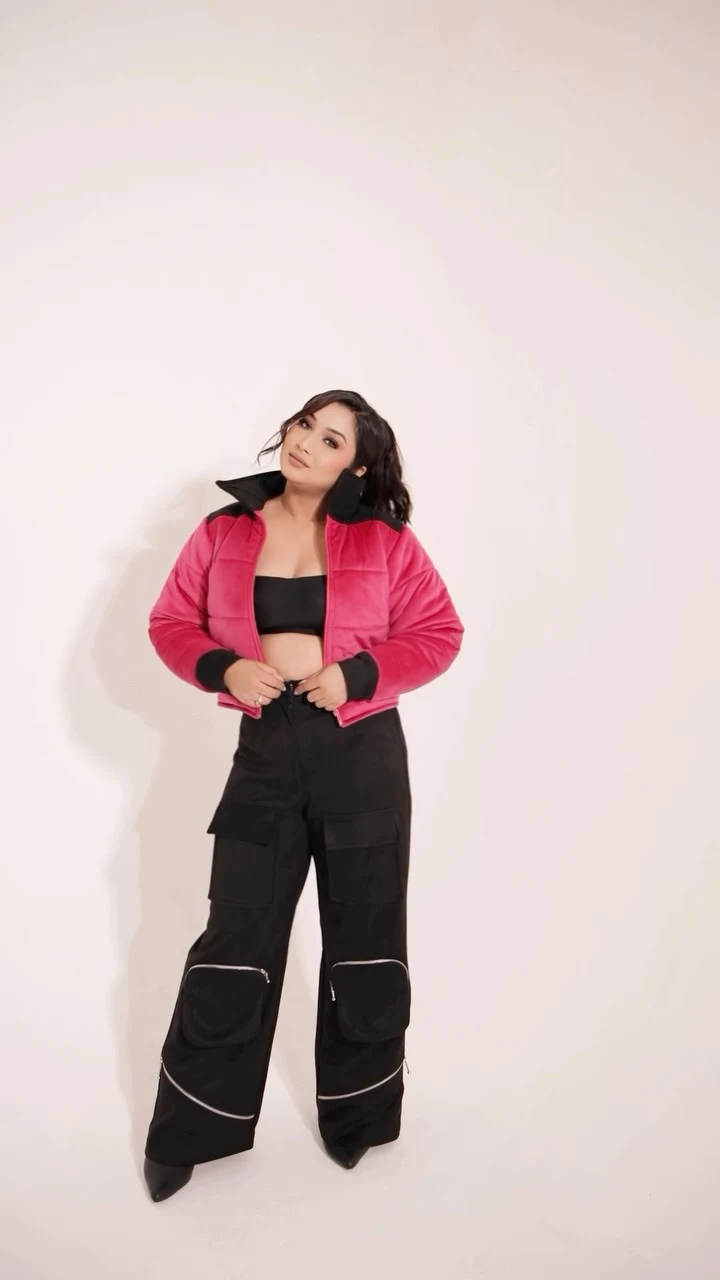 Bright pink cropped puffer jacket over black bandeau top, wide-leg cargo pants, and black pointed shoes.