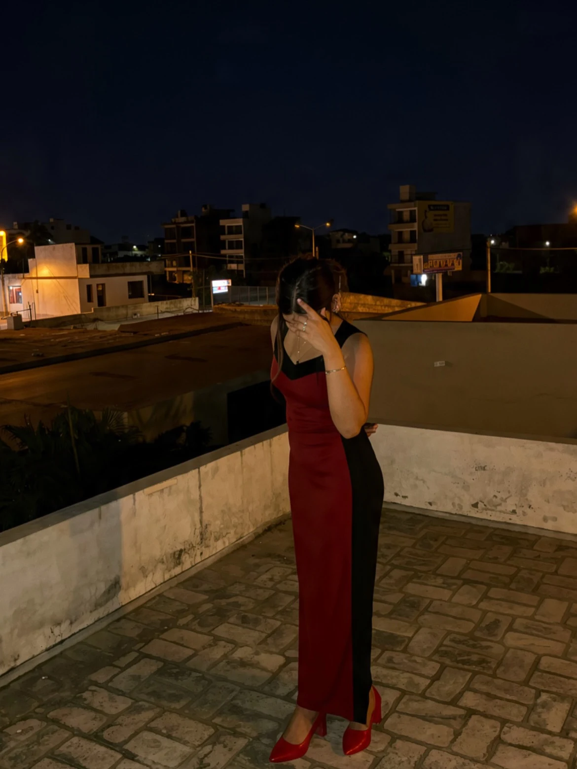Long sleeveless form-fitting dress red down center front and black on sides with high side slit and red pointed-toe heels