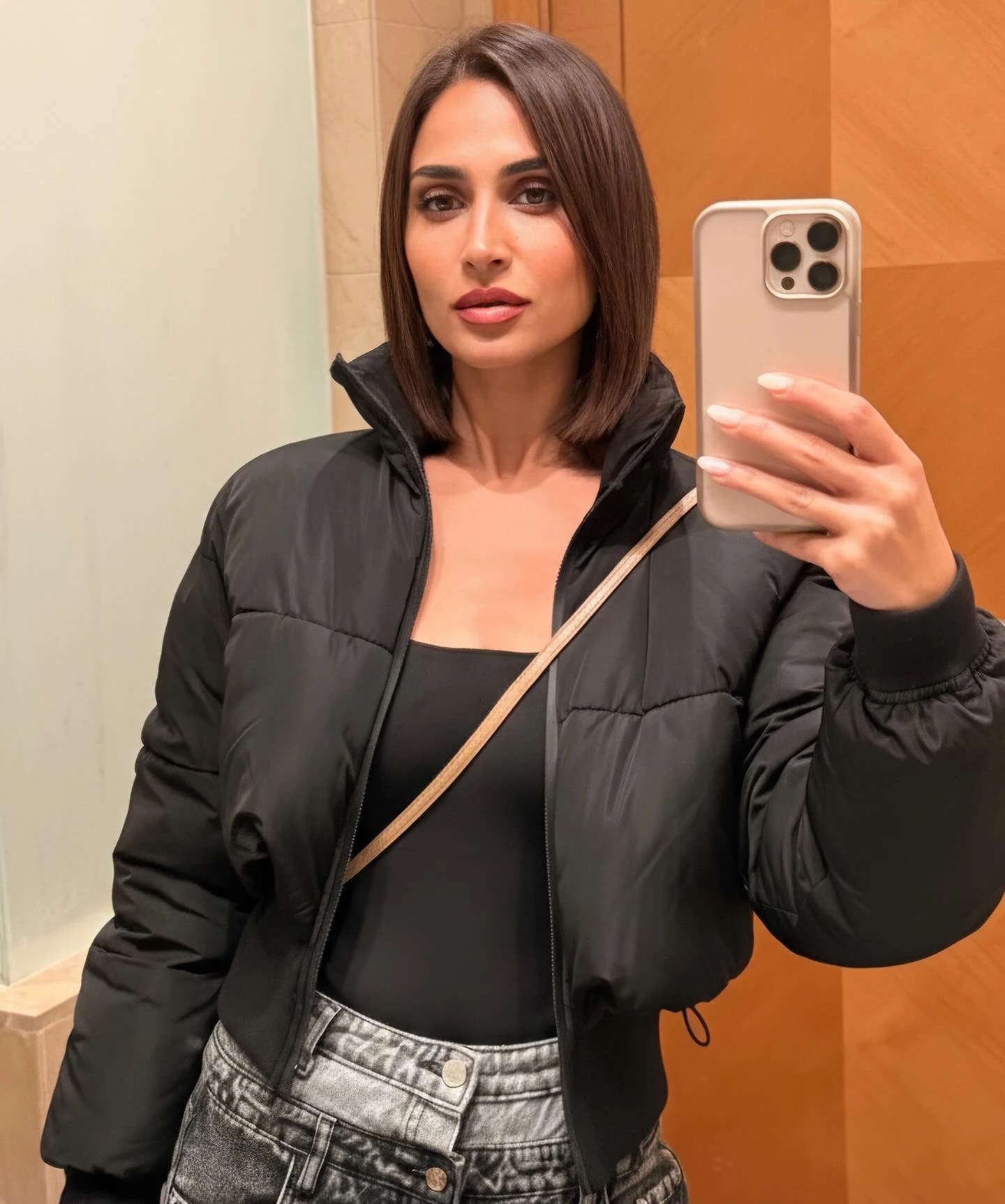 black cropped puffer jacket with high collar, black scoop neck bodysuit, high waisted acid wash denim jeans