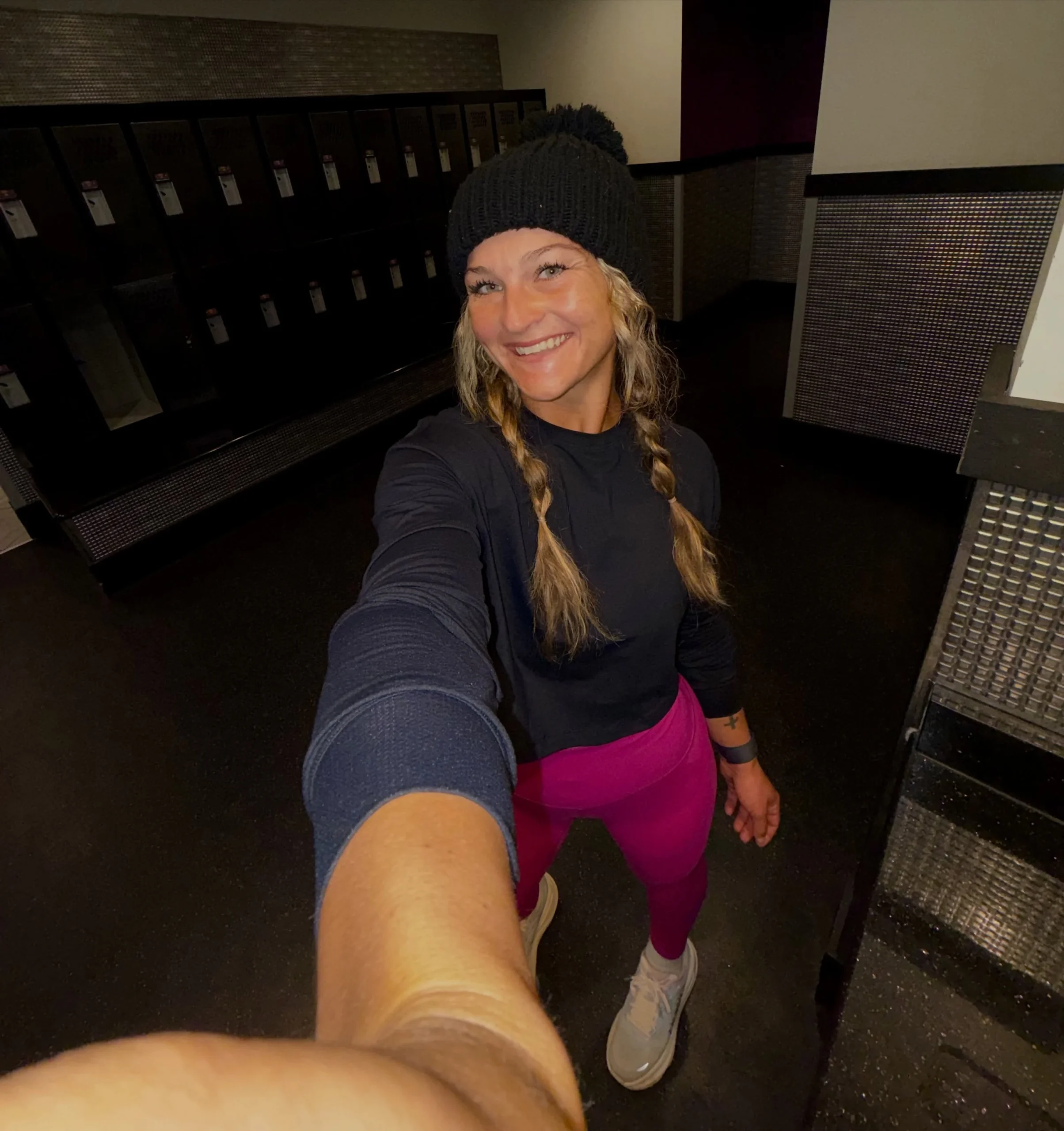 Person in a fitted black long-sleeve top, bright magenta leggings, and a black ribbed knit beanie.