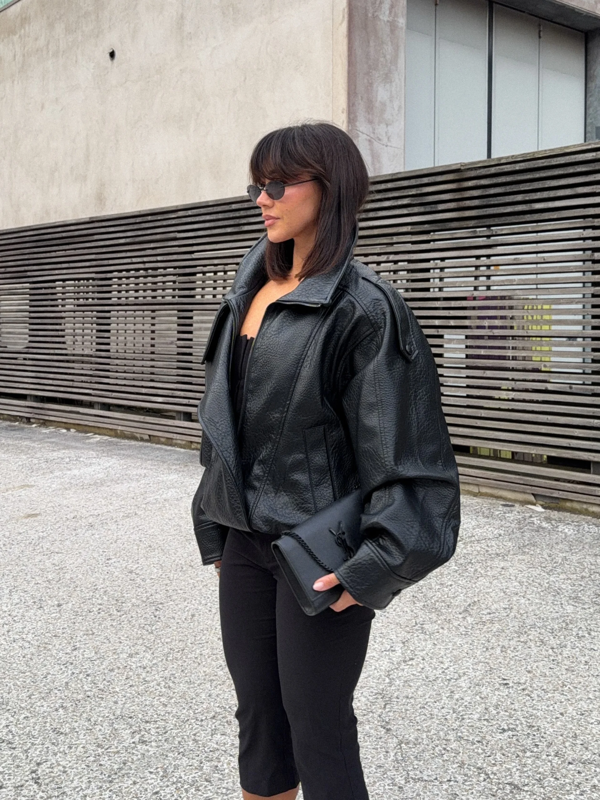 Black leather moto jacket over capri leather trousers with pointed slingback heels and oval sunglasses.