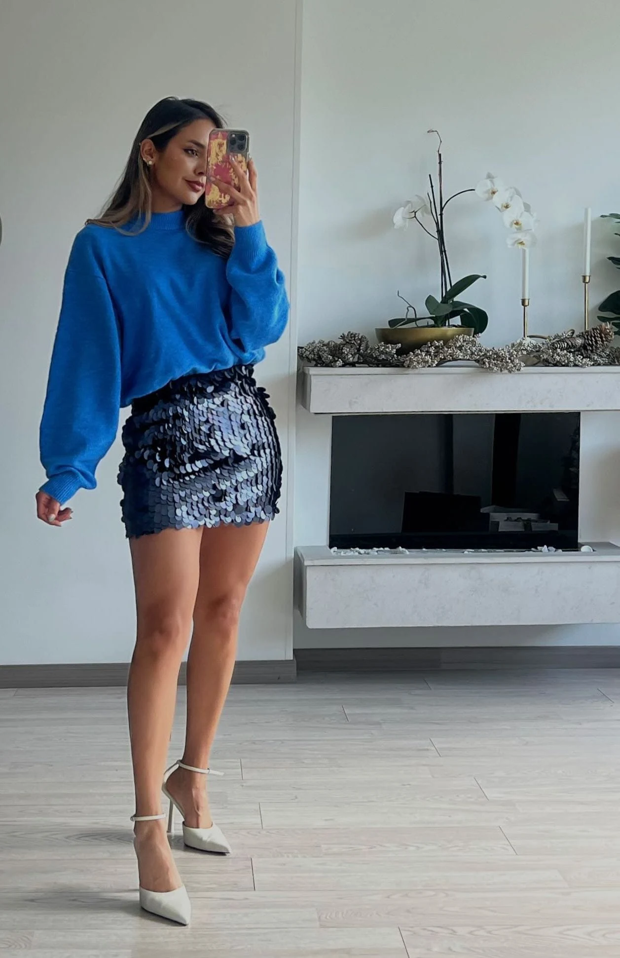 Blue oversized sweater tucked into a shimmering blue sequin mini skirt styled with heels.