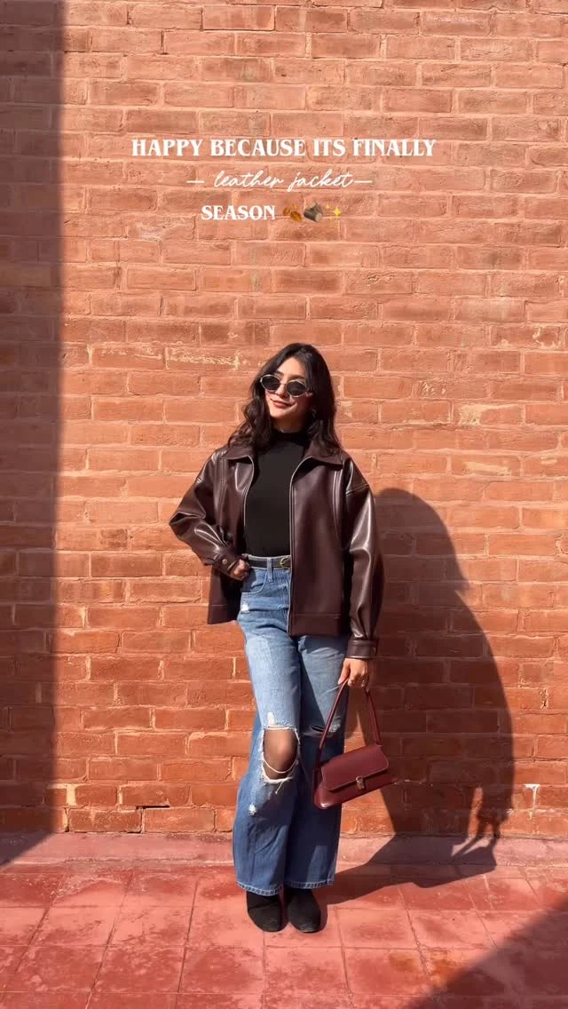 Dark brown leather bomber jacket, black turtleneck, light-wash wide-leg ripped jeans, black ankle boots