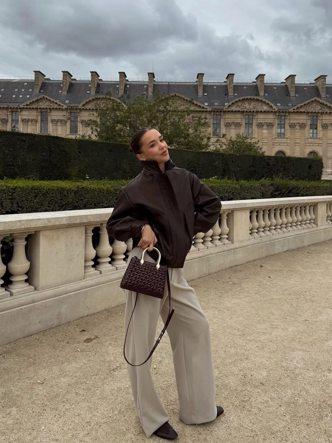 An oversized dark brown leather jacket worn with wide-leg light beige trousers is a country chic combination that leans into the modern, city-country crossover end of the aesthetic — the leather jacket references countryside riding heritage while the wide-leg trouser keeps the silhouette contemporary and fashion-forward. The contrast between the dark, structured leather and the fluid, light-toned trouser is what gives this its visual interest: the weight of the jacket on top is balanced by the movement of the trouser below, and the brown-to-beige tonal shift creates warmth without heaviness. What I love about this is how it translates the countryside aesthetic into an urban setting without losing any of its essential character.