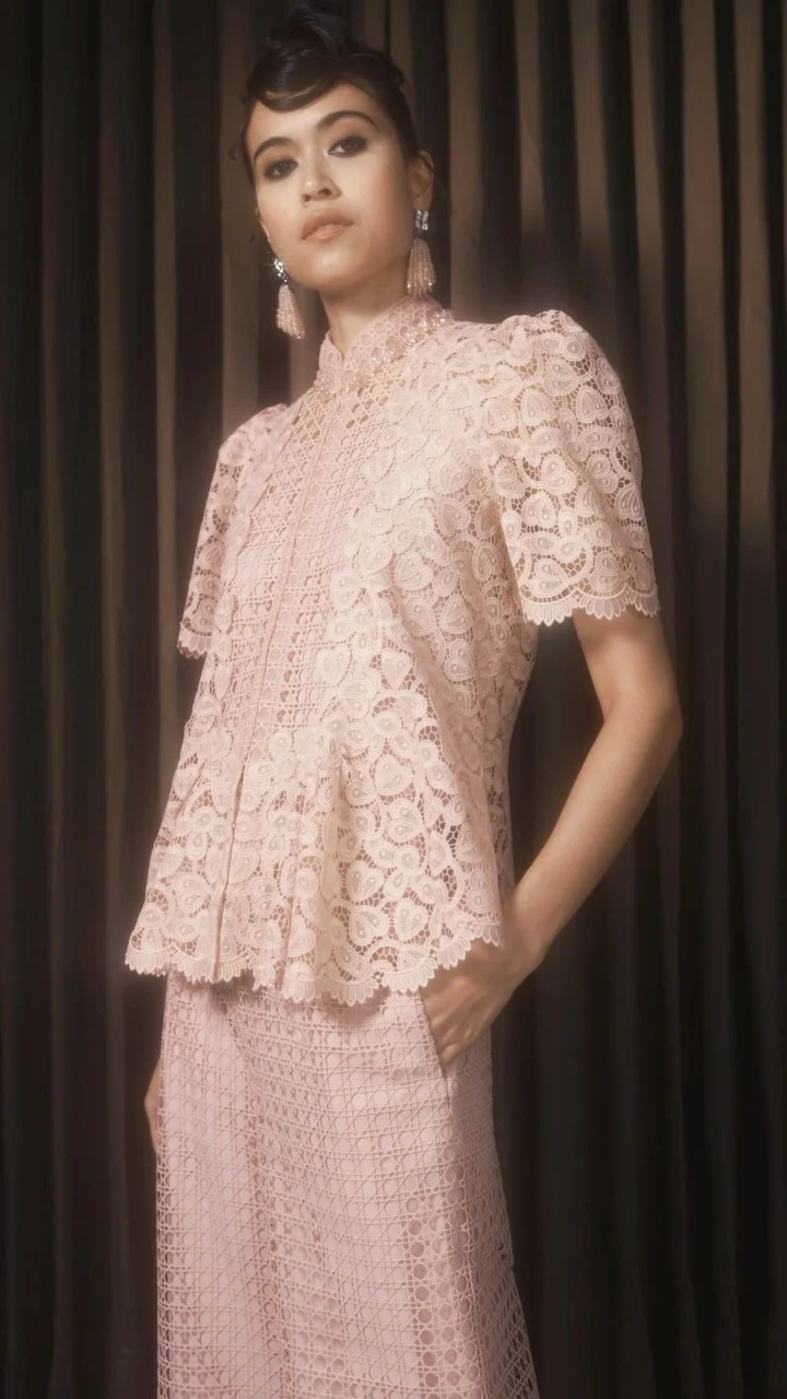 Pale pink lace two-piece with puffed-sleeve high-neck blouse and long matching skirt with geometric pattern.