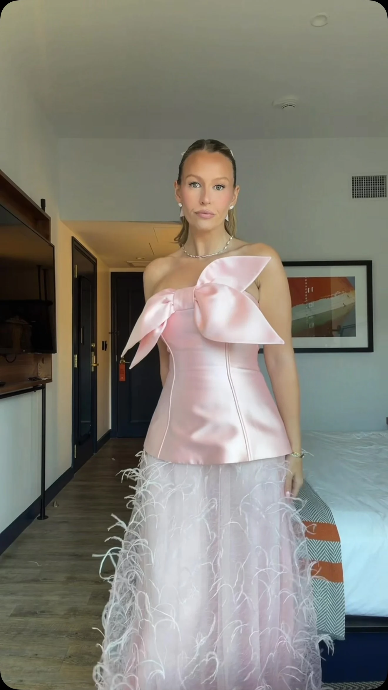 Pink satin strapless corset top with oversized bow paired with a feather-trimmed long skirt.