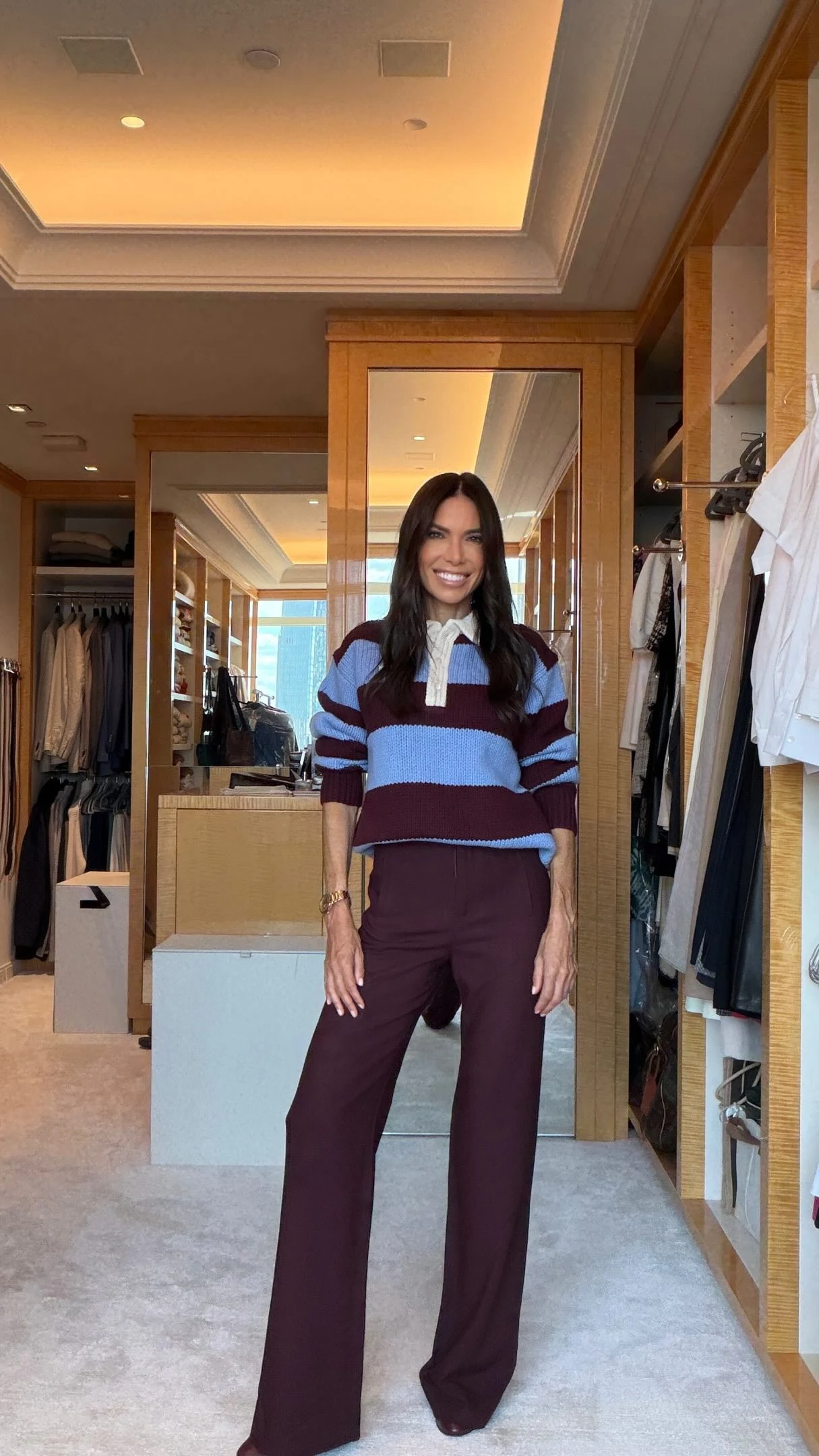 Woman wearing a red and camel striped cardigan with light wash jeans.