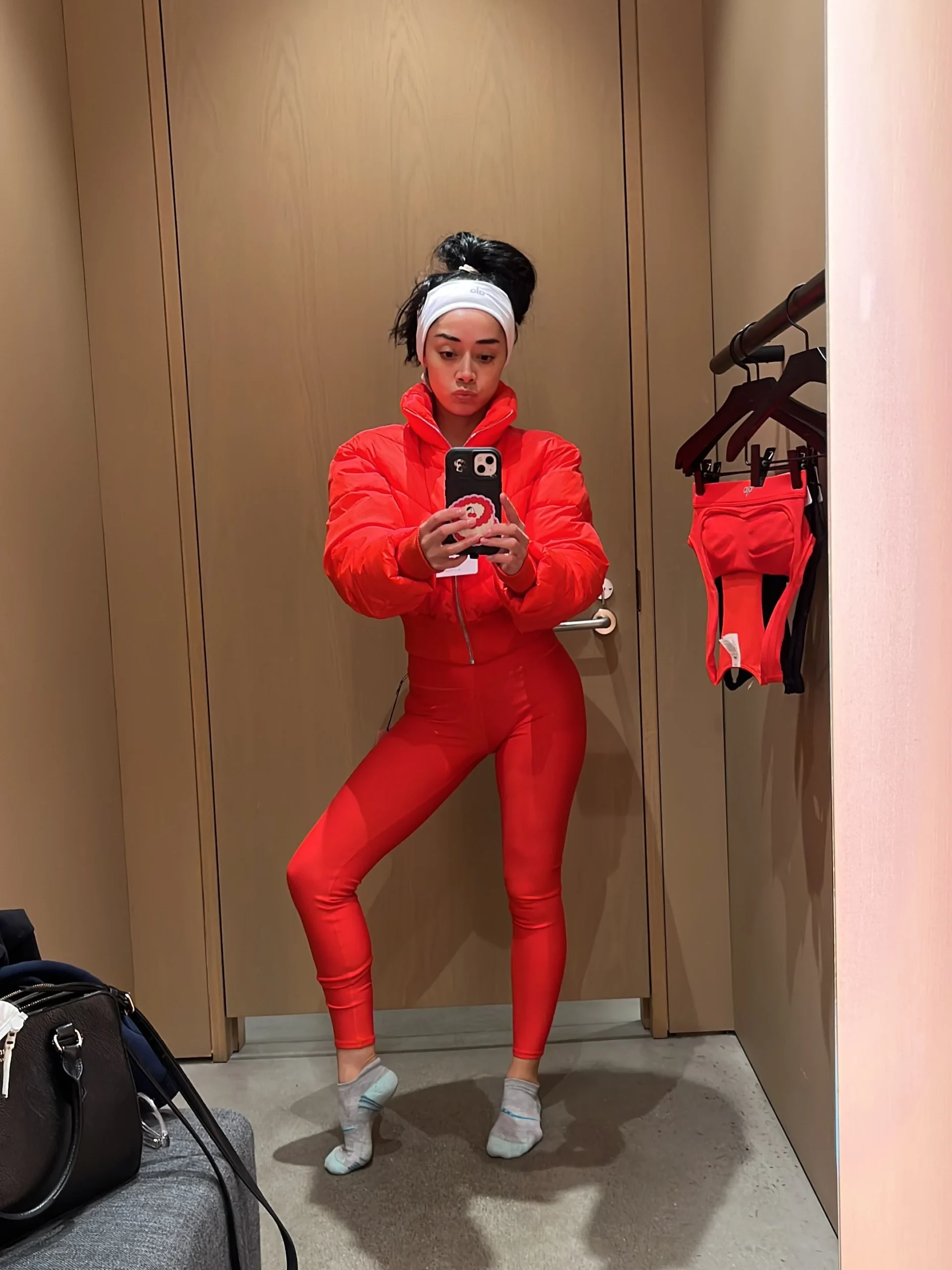 Bright red cropped puffer jacket and matching red leggings worn with a white headband and light gray socks.