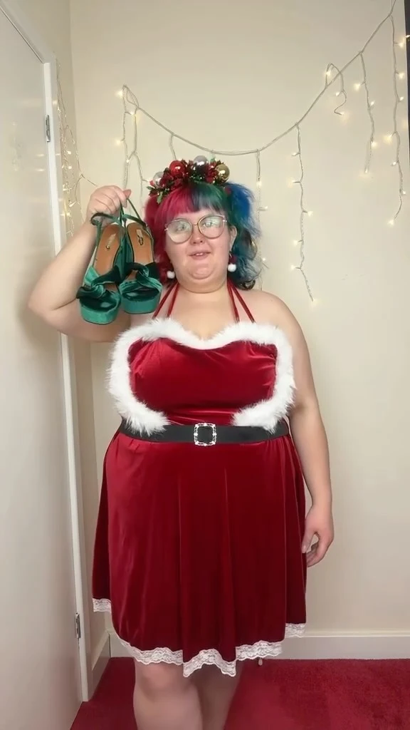 Red halter dress with white fluffy trim, black belt, and dark green shoes held beside the outfit.