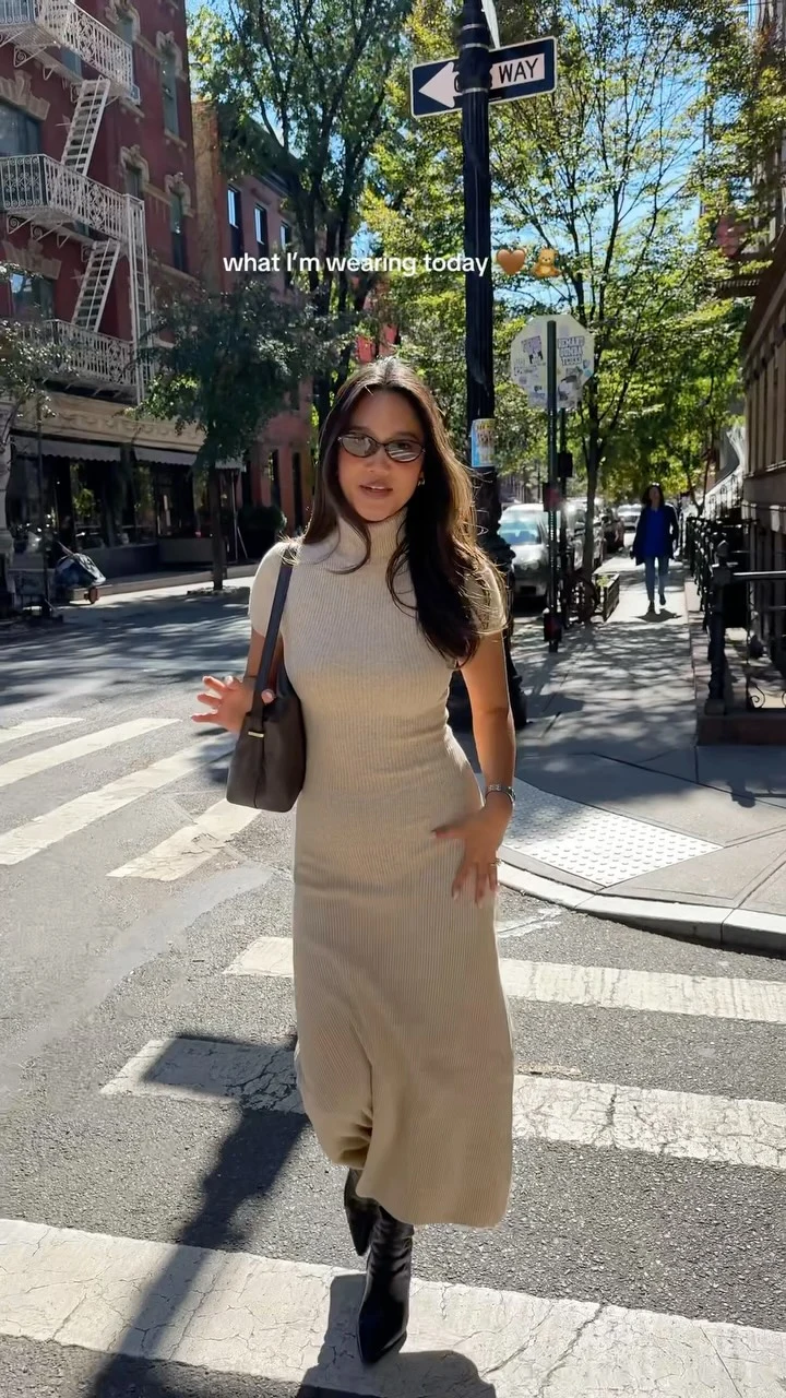 Fitted beige ribbed midi dress with black knee-high boots and a dark shoulder bag on a city street.