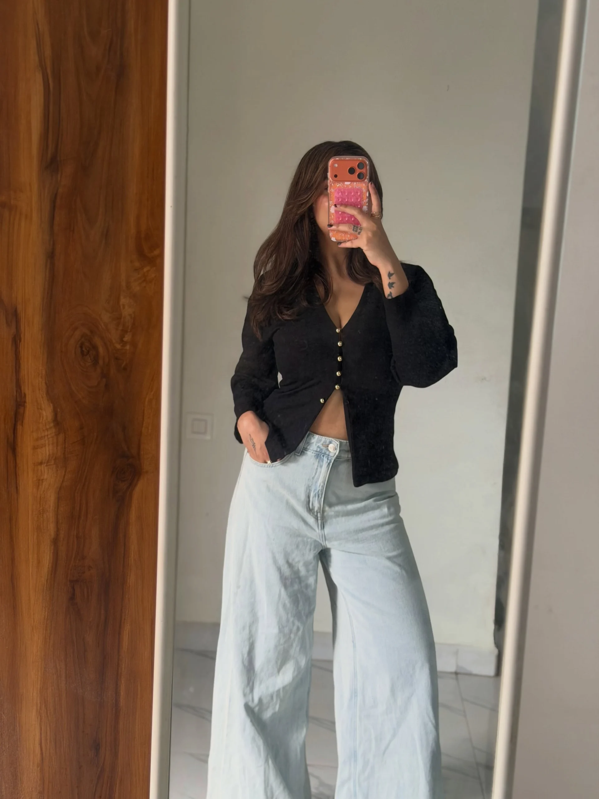 Black cropped cardigan over a white top with light-wash high-waisted wide-leg jeans.