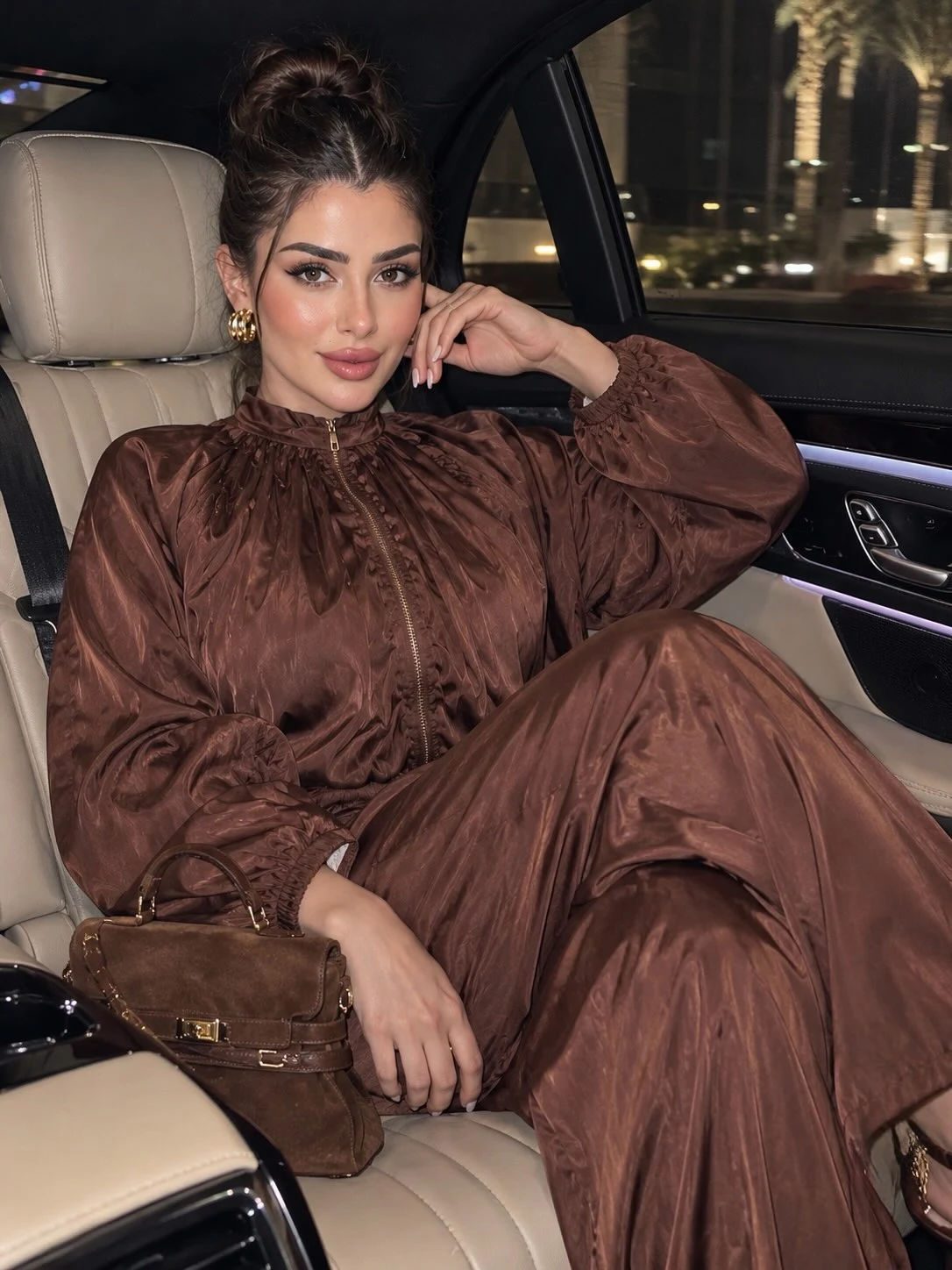 Matching brown high-neck blouse and wide-leg trousers with a structured brown handbag.