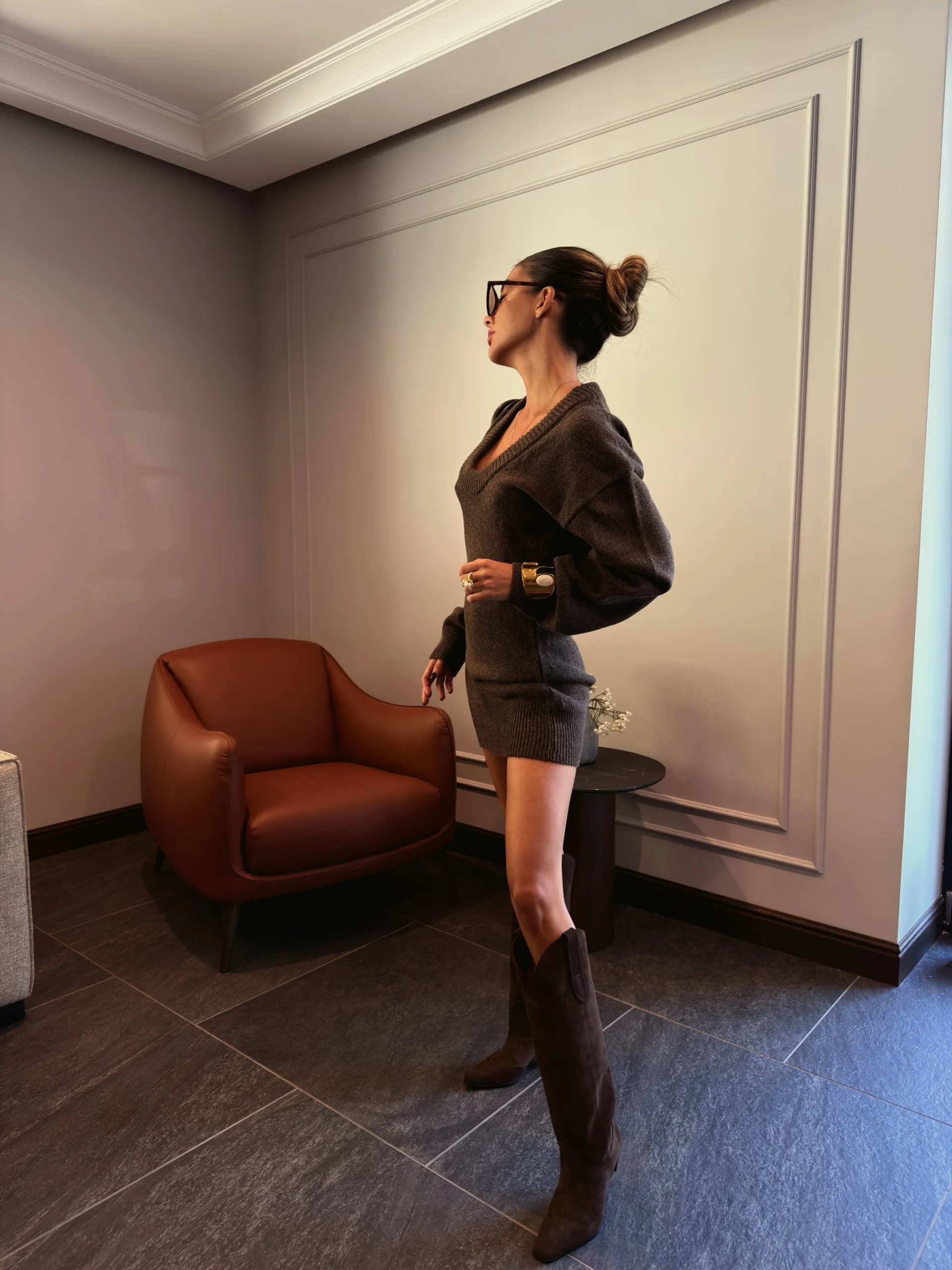 Oversized brown knit sweater dress styled with matching suede cowboy boots and a brown shoulder bag.