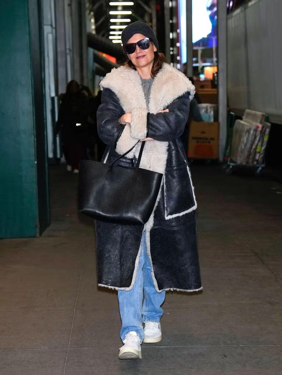 Katie Holmes walks in New York City wearing a long coat and neutral winter layers.