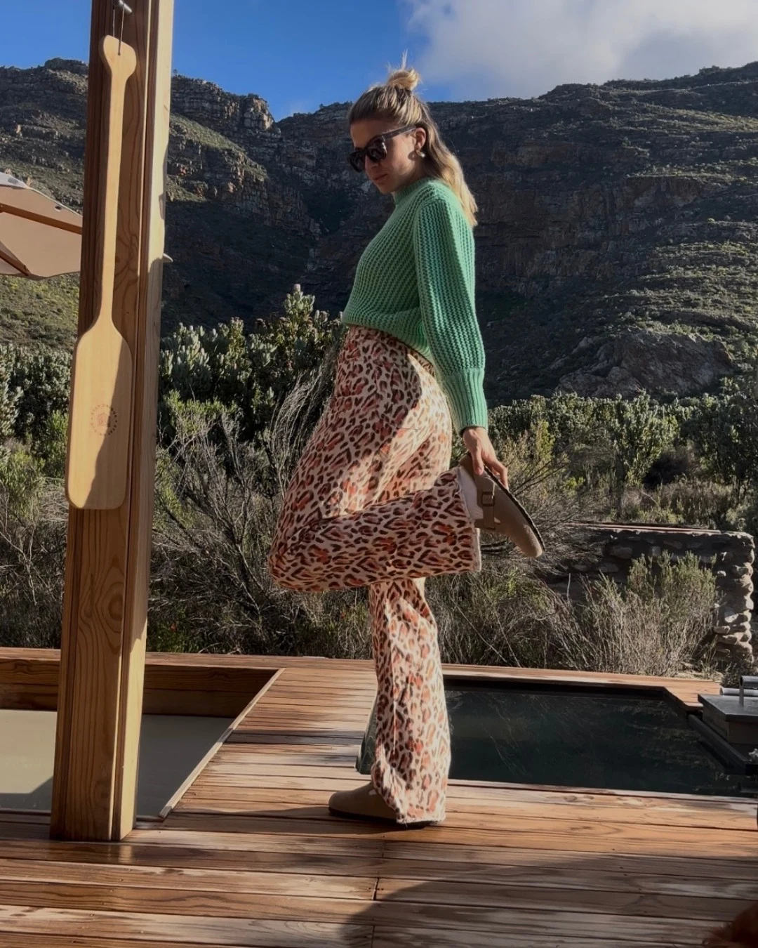 chunky mint-green knit sweater tucked into high-waisted wide-leg leopard print trousers, white sock, tan Boston clogs