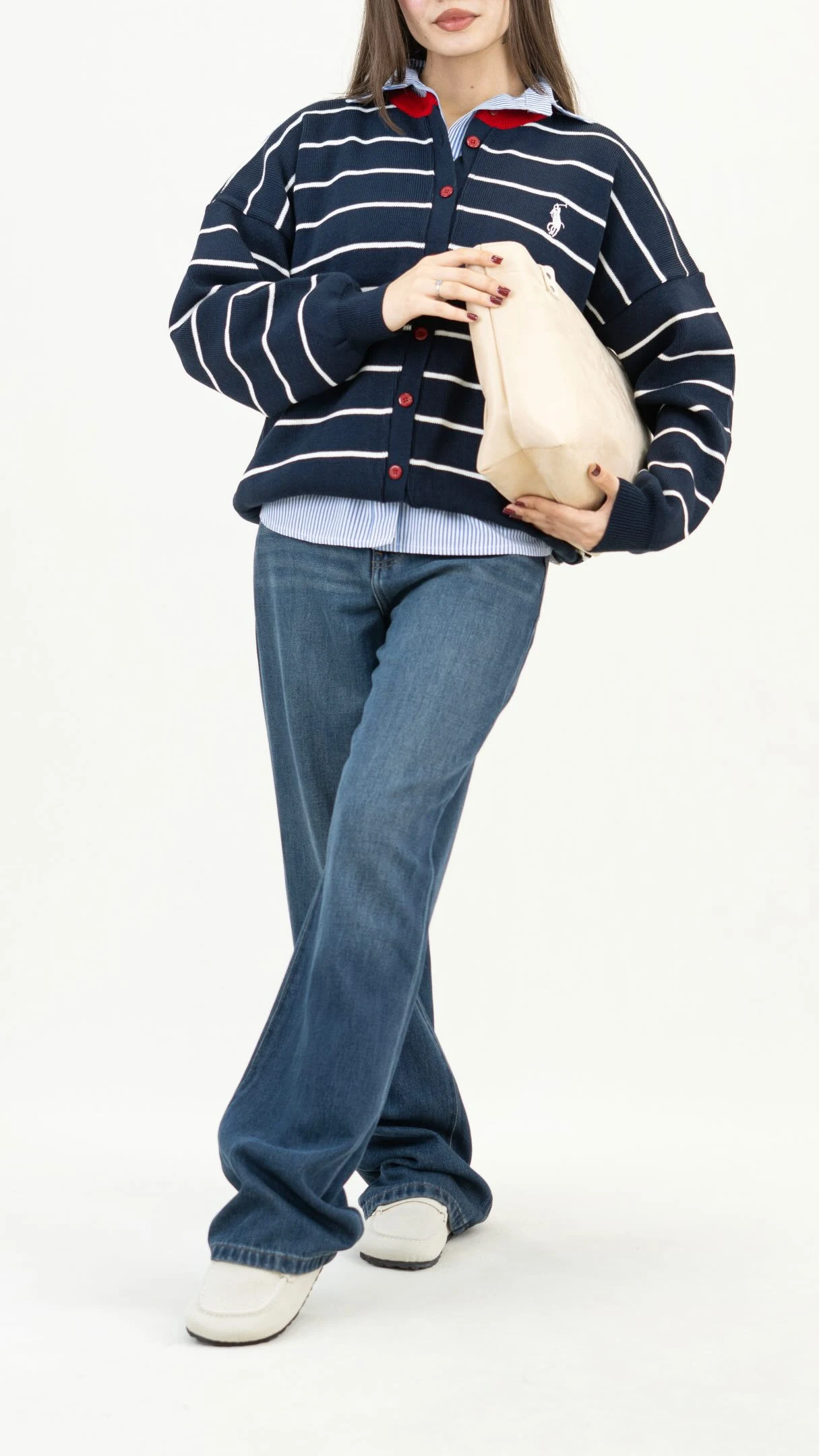 Navy cardigan with white stripes and red buttons over light blue striped shirt, dark blue wide leg jeans, cream loafers, beige tote