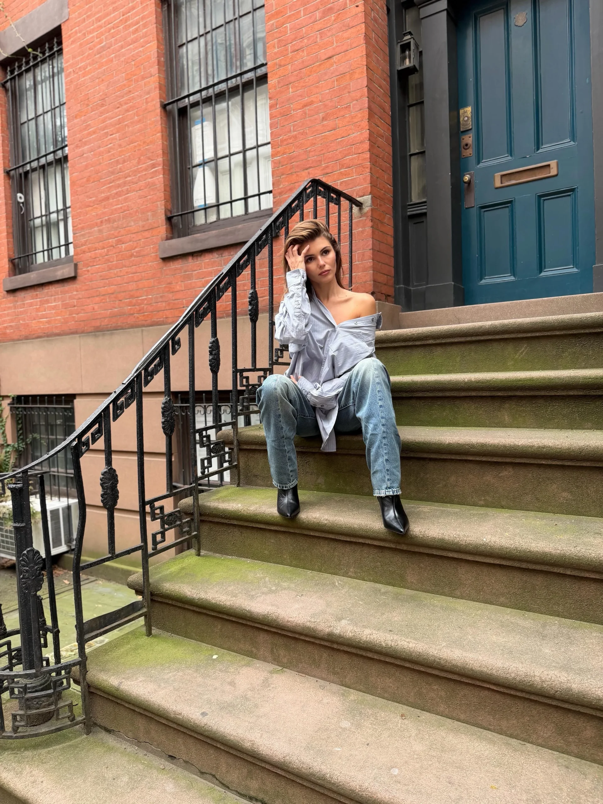 Oversized light-blue button-down shirt styled with black tights and brown leather ankle boots.