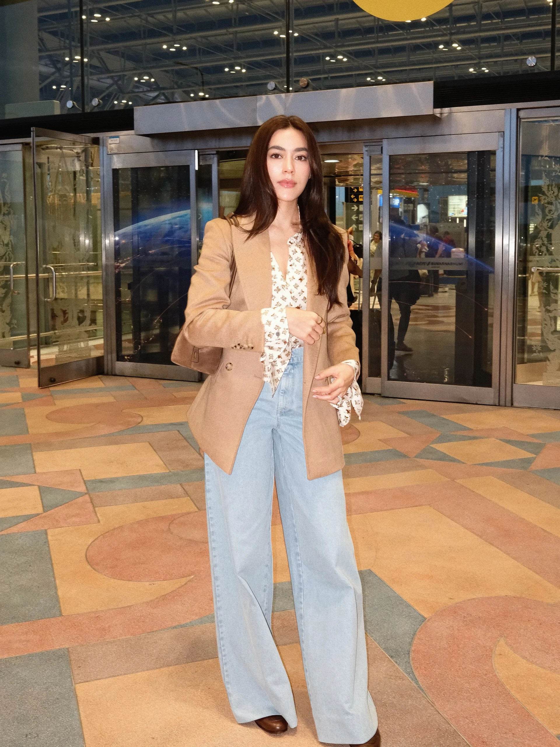 Tan blazer over floral blouse with high-waist wide-leg light-wash jeans and brown shoes.