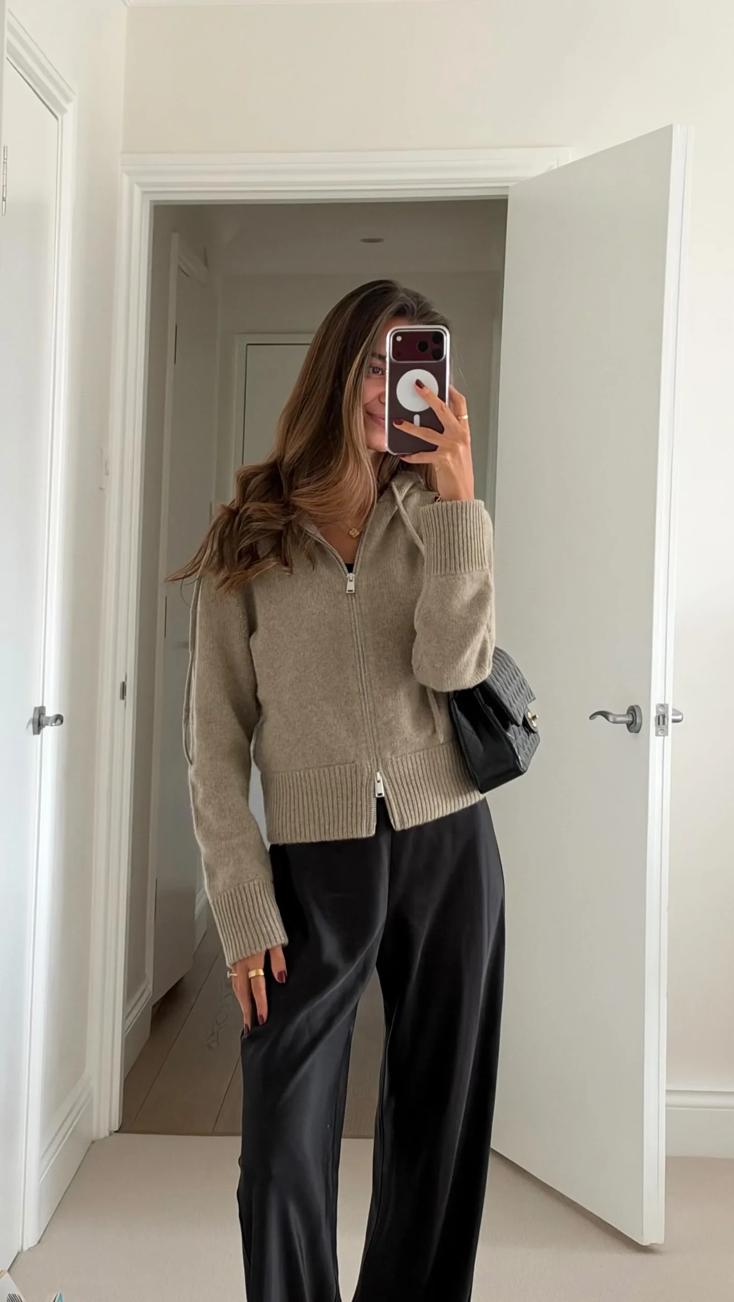 Light taupe hooded zip cardigan worn with black wide-leg trousers and a black shoulder bag.