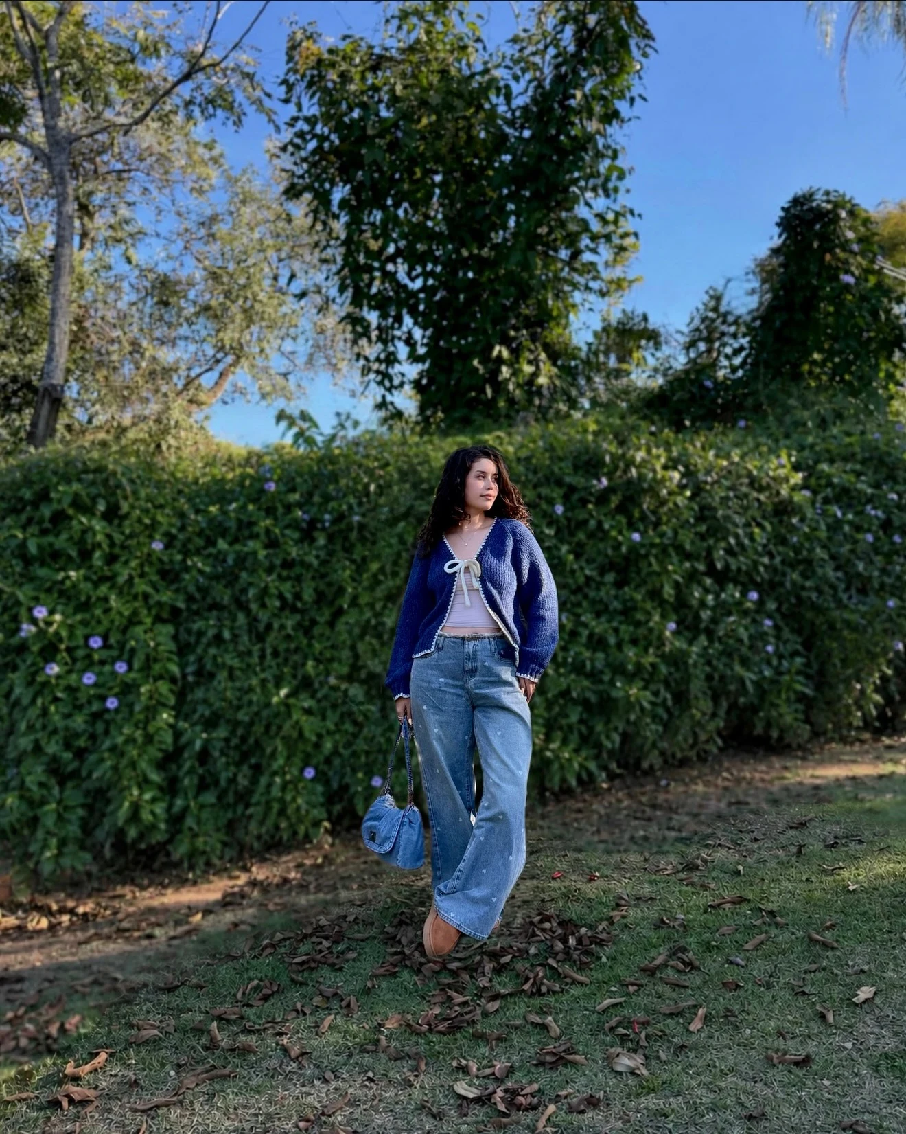 Dark blue knit cardigan over a light blue button-down shirt with blue straight jeans.