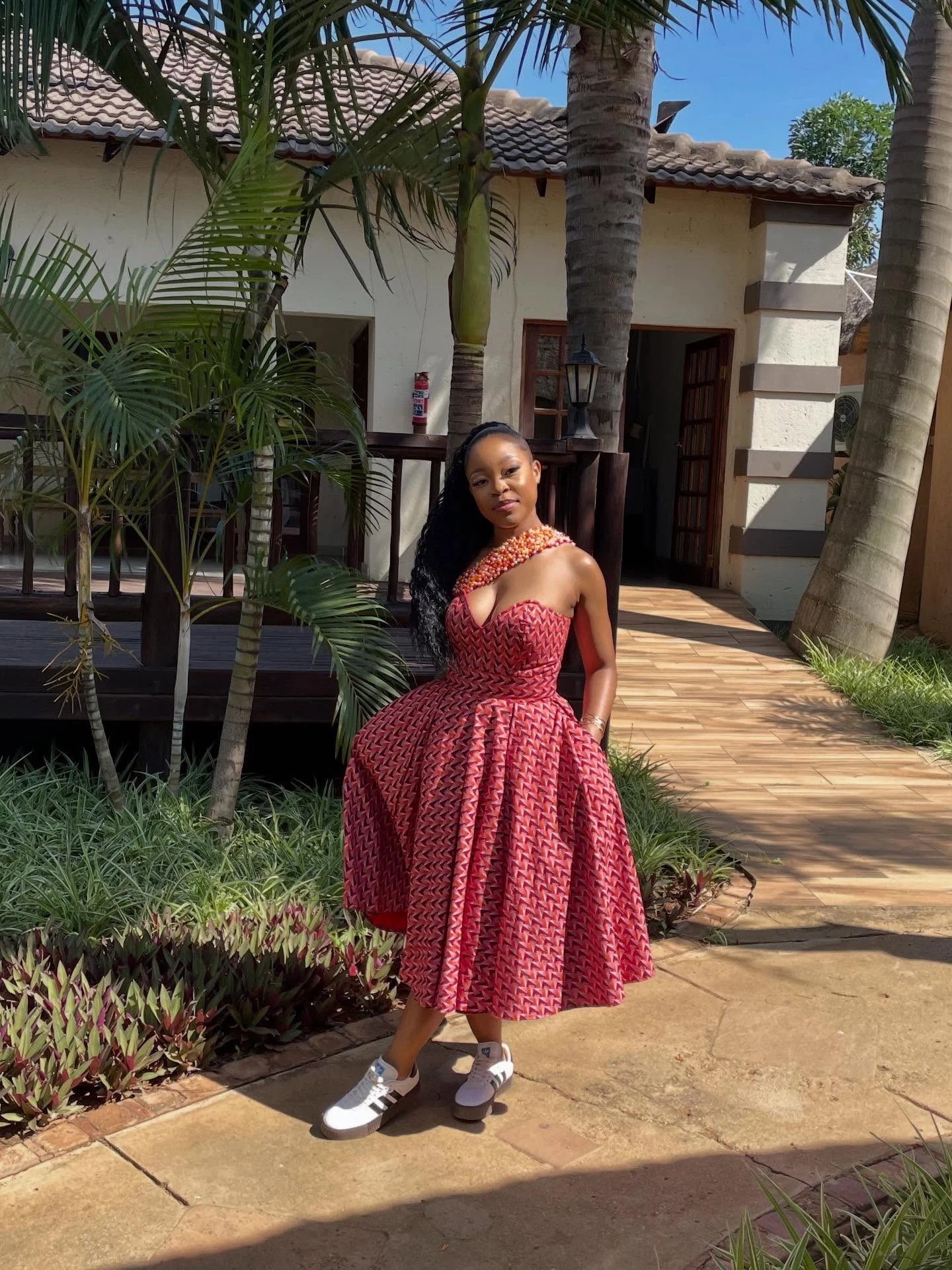 Red and pink geometric one-shoulder midi dress styled with white Adidas Samba Rose Platform sneakers.
