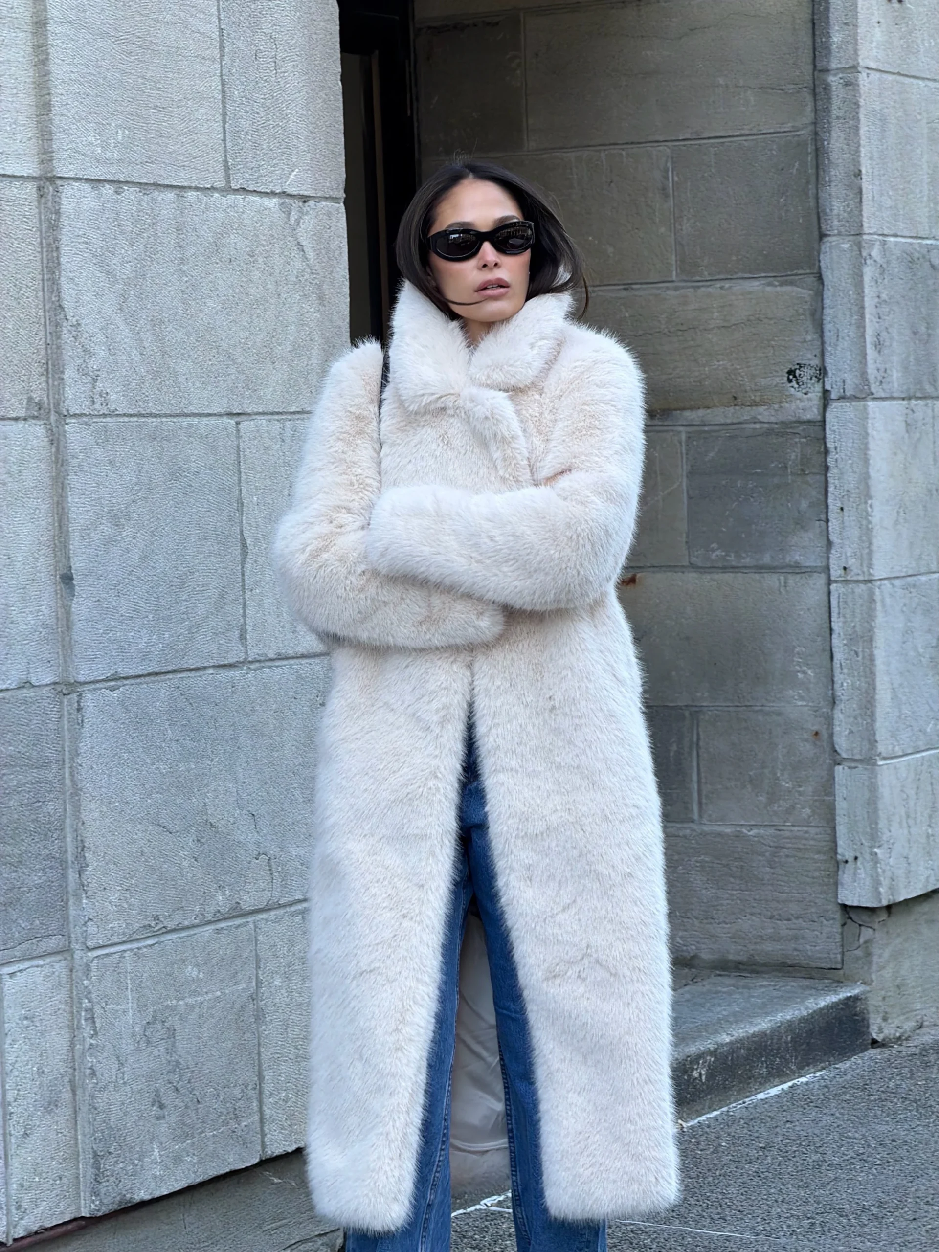 Woman wearing an all-black outfit with a wool coat, turtleneck, cropped trousers, and heels.
