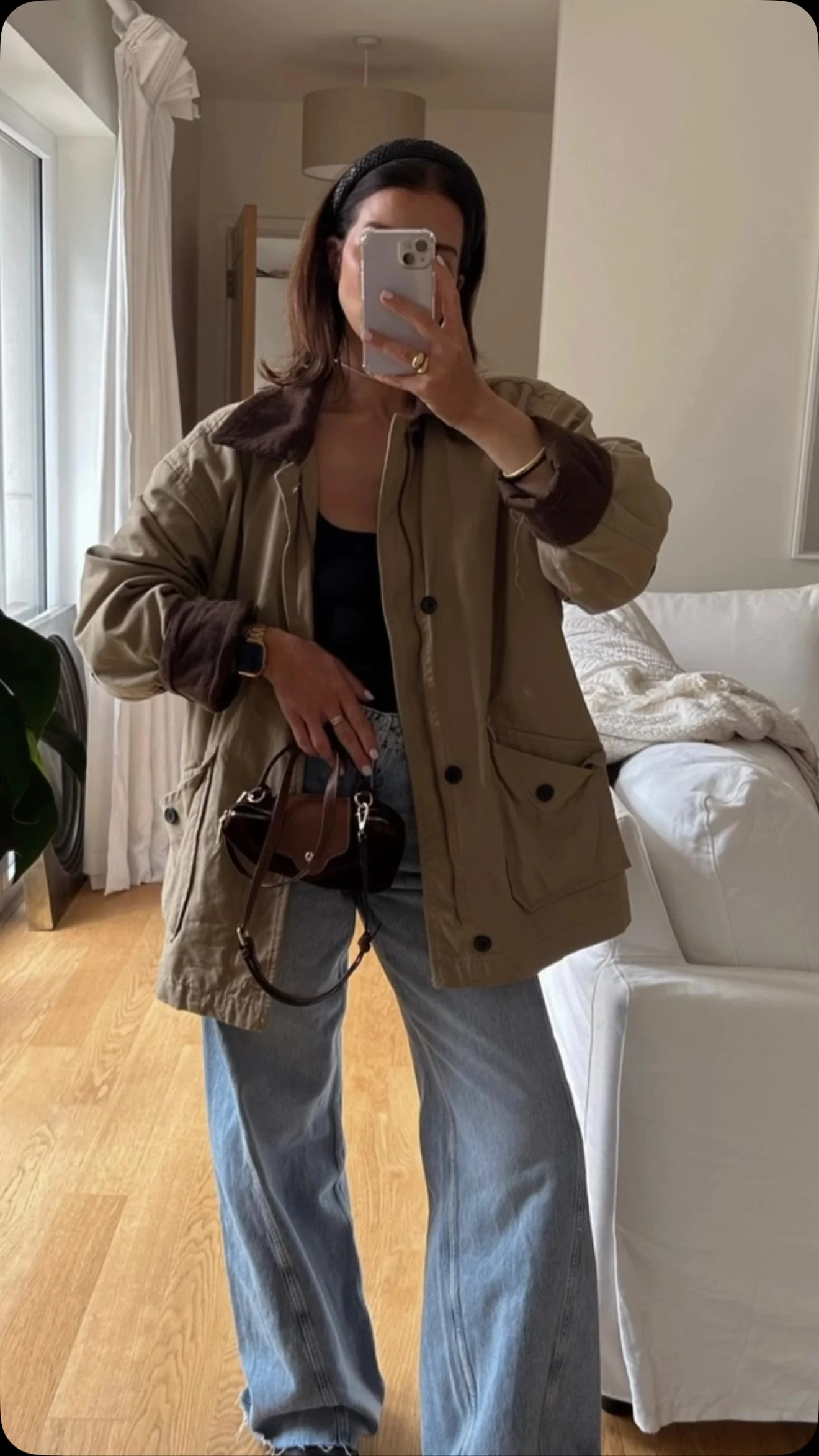 Person in a long taupe wool coat, black beanie, sunglasses, black leggings, and cream slippers.