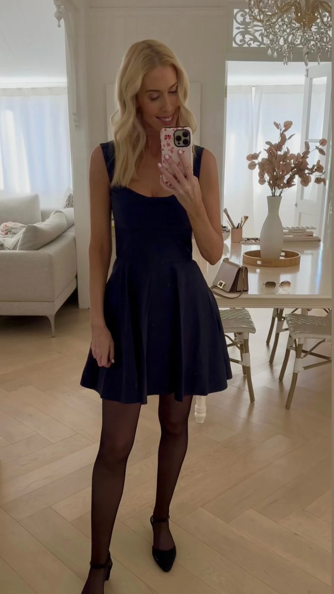 Navy sleeveless fit-and-flare dress styled with sheer black tights and black ankle-strap heels.