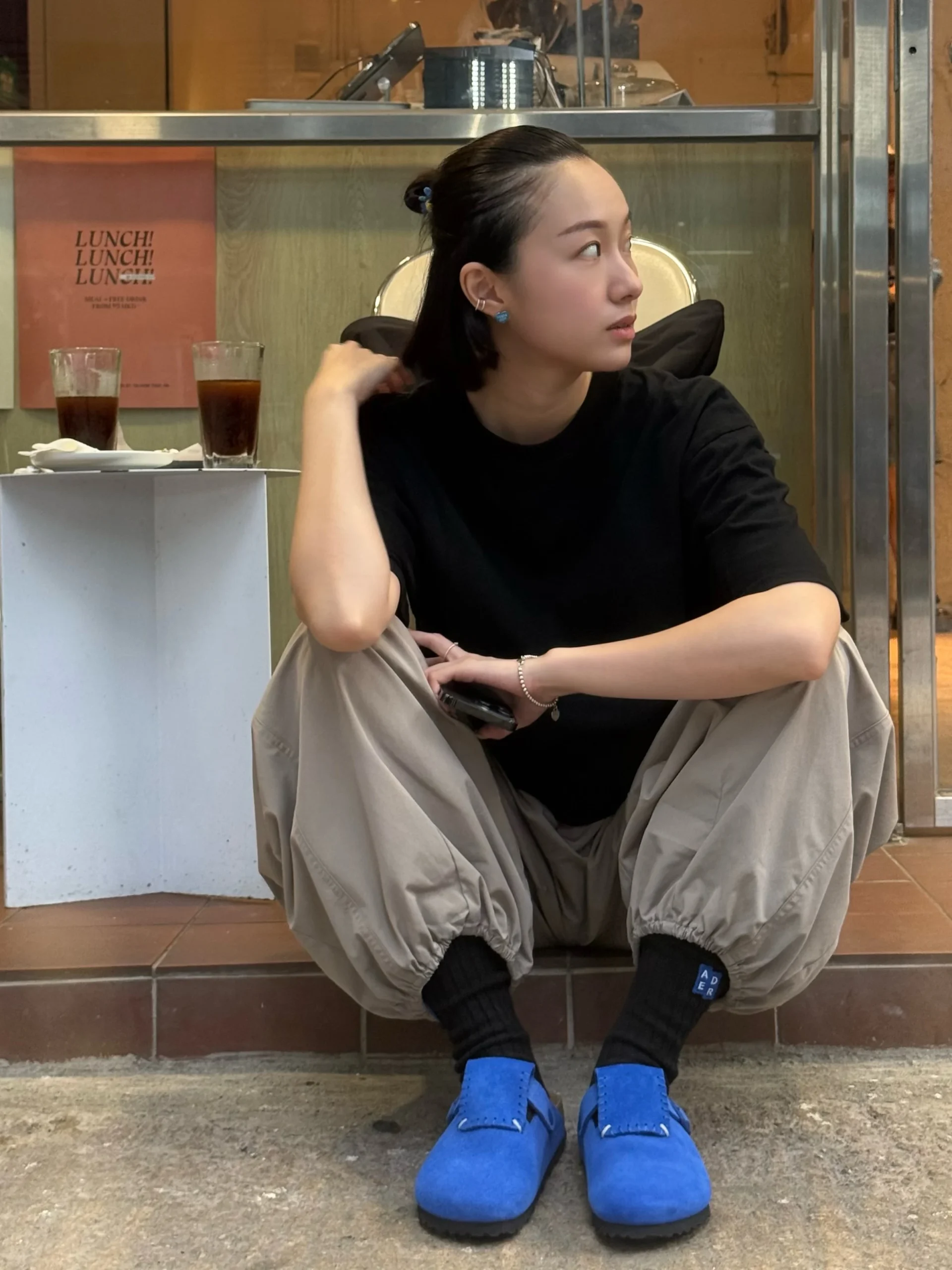 oversized black t-shirt, loose beige trousers, black crew socks, bright blue Boston clogs
