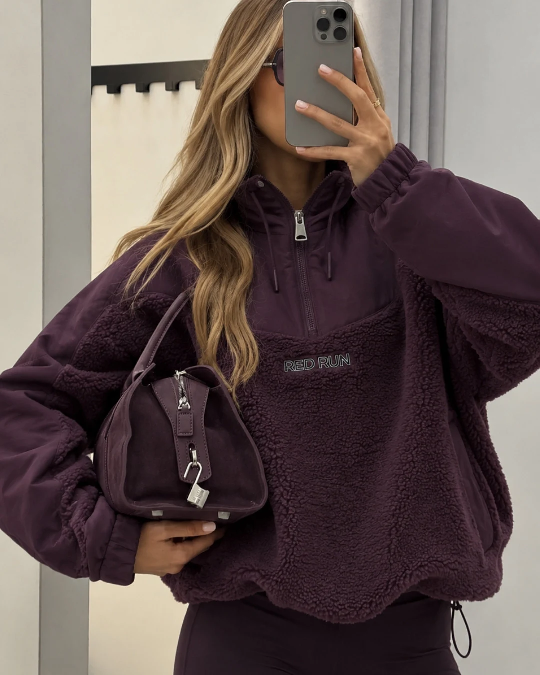 Oversized deep plum quarter-zip fleece pullover with hood drawstrings and dark fitted bottoms.