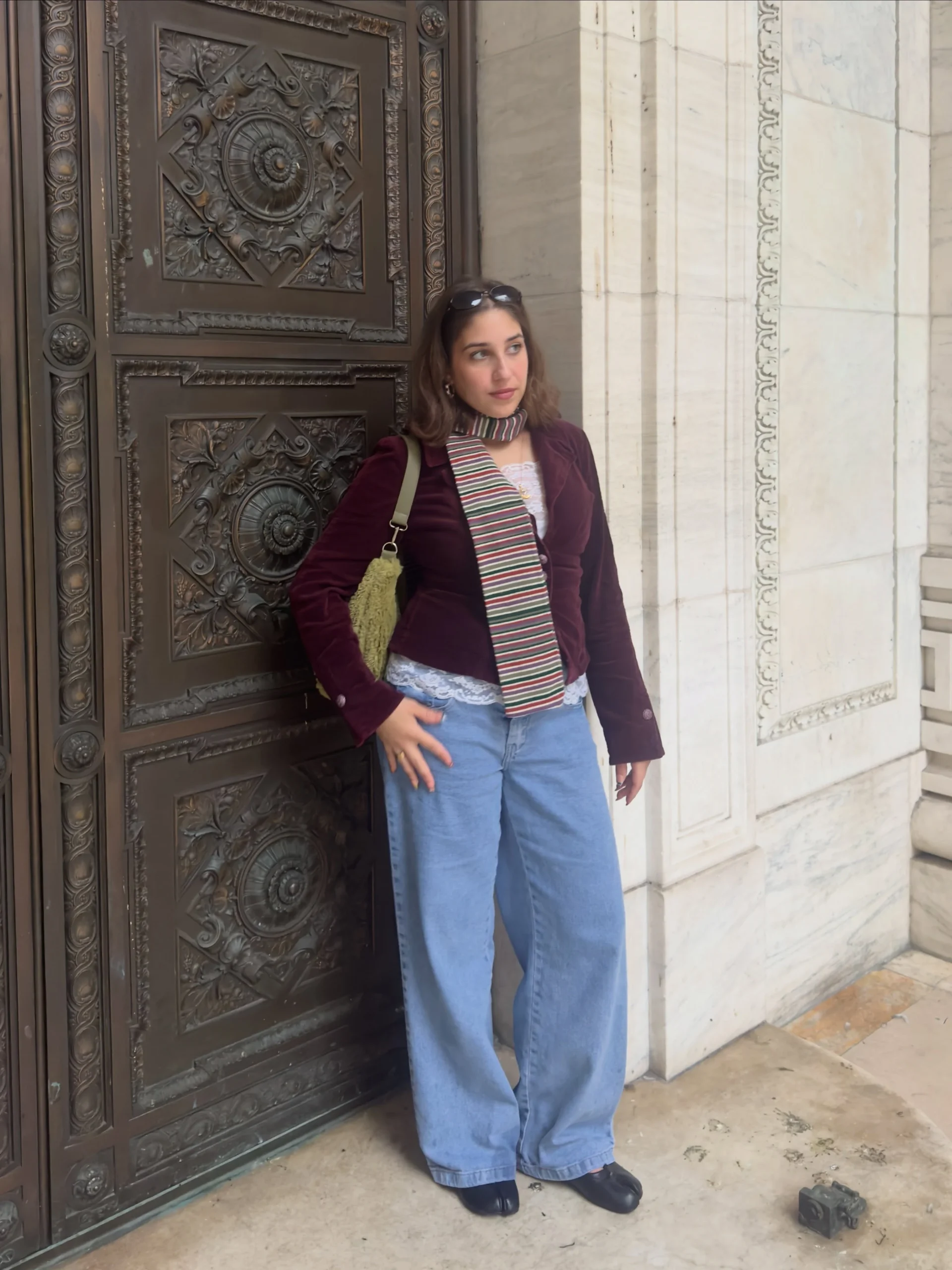 Plum velvet blazer over a white top, dark blue wide-leg jeans, black belt, and brown shoulder bag.