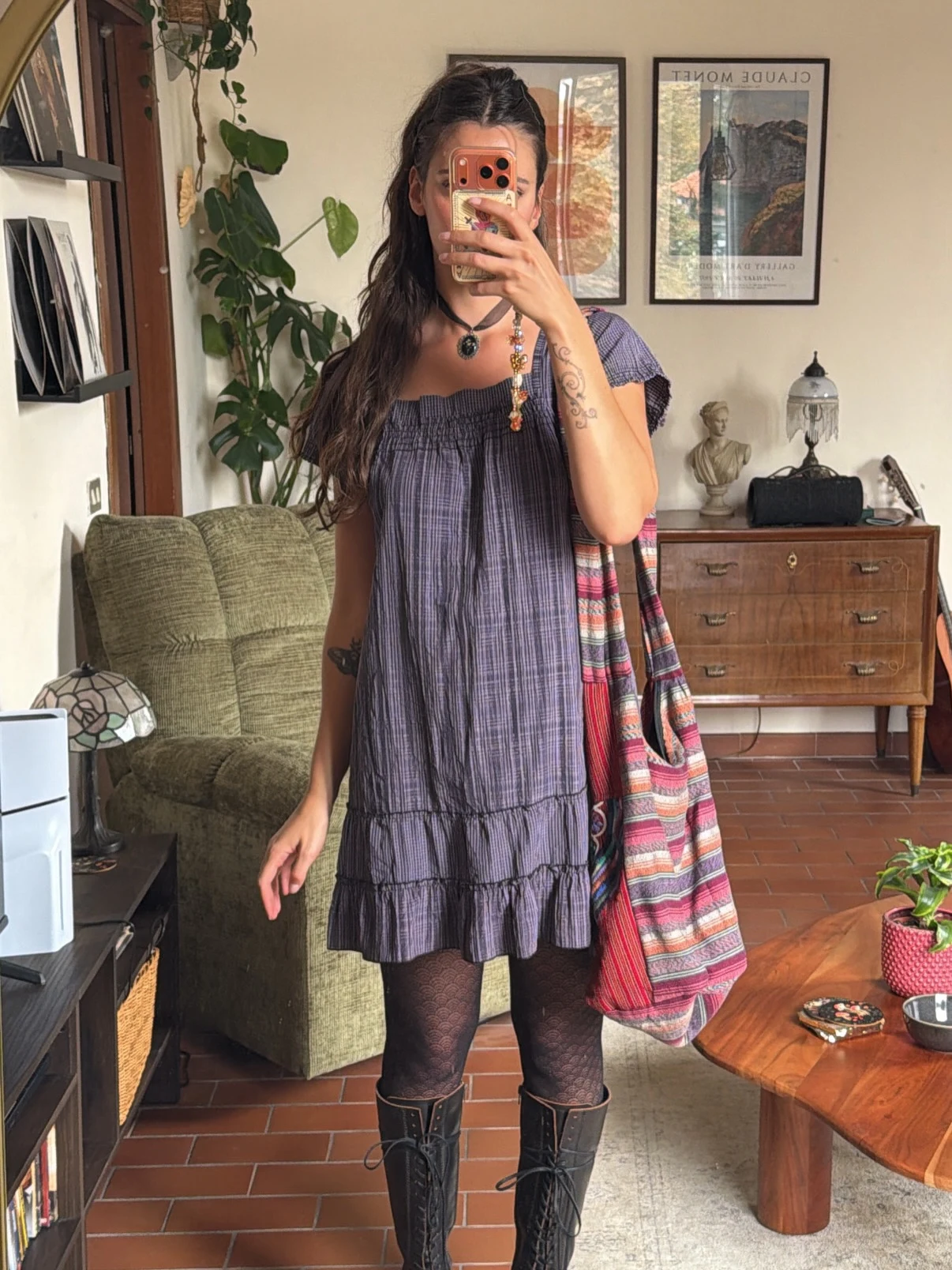 Purple-gray plaid tiered mini dress styled with dark patterned tights, tall black boots, and a striped tote.