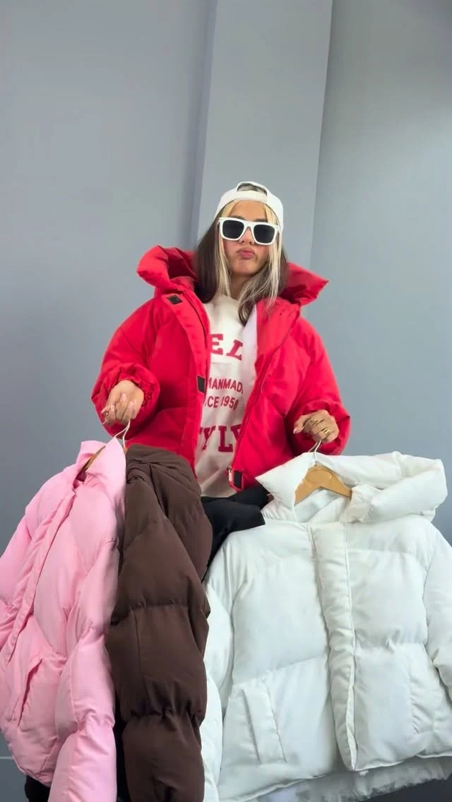 Bright red cropped puffer jacket over a white graphic sweatshirt with dark trousers.