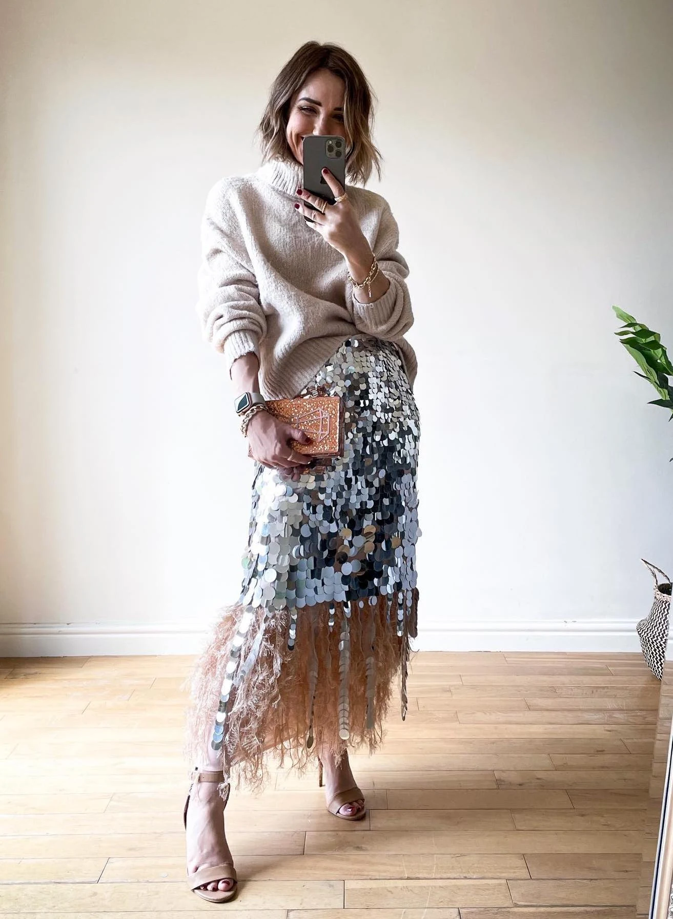 Silvery sequin midi skirt with pink feather hem styled with a beige sweater and nude heels.