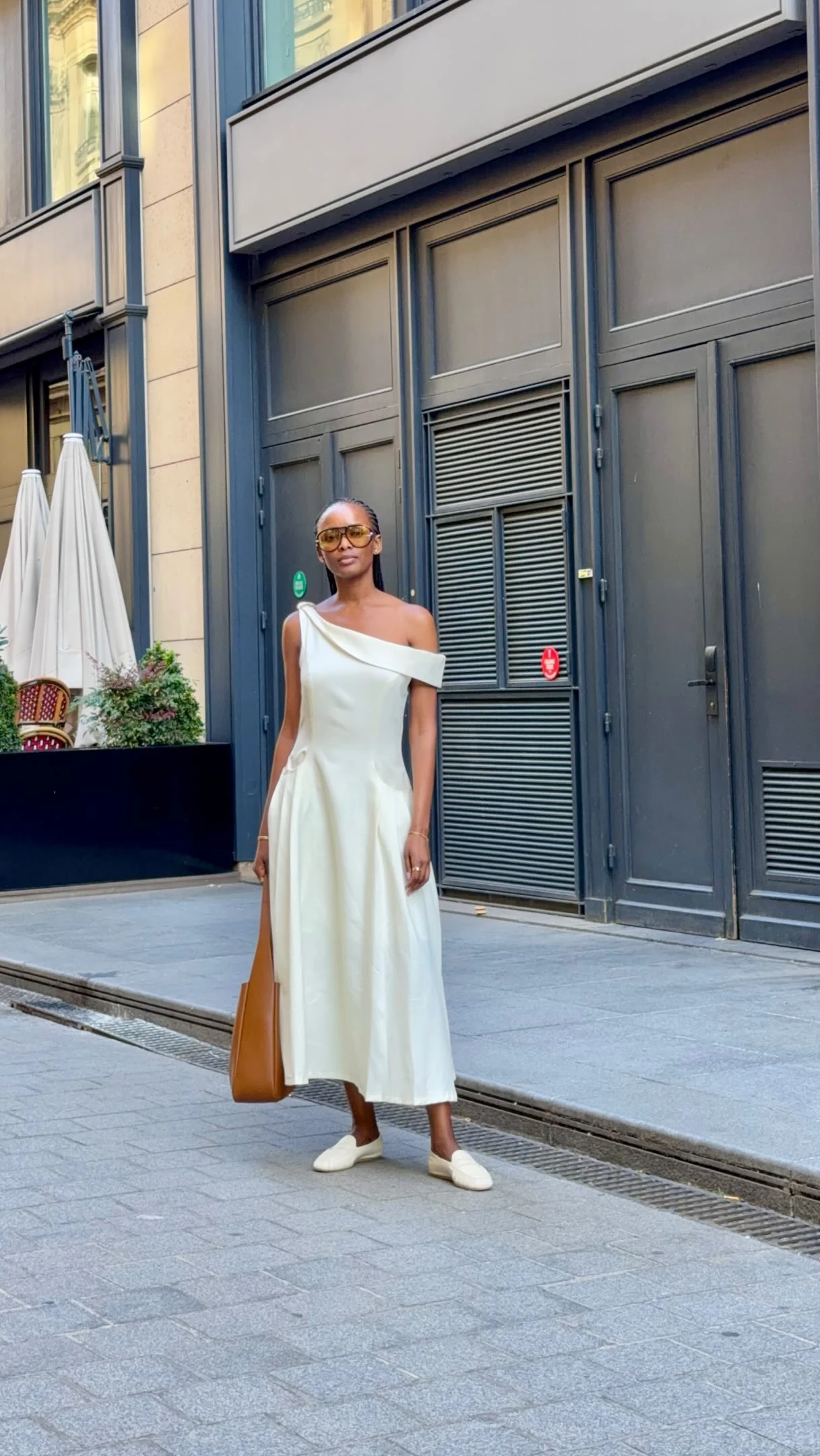 Woman in a long white off-the-shoulder dress with a fitted bodice and flowing skirt.