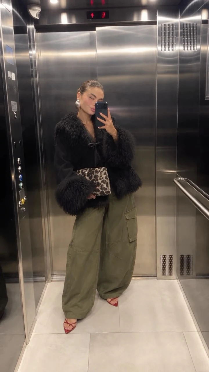 Black shaggy-trim jacket with olive cargo pants, red strappy heels, and an animal print clutch.