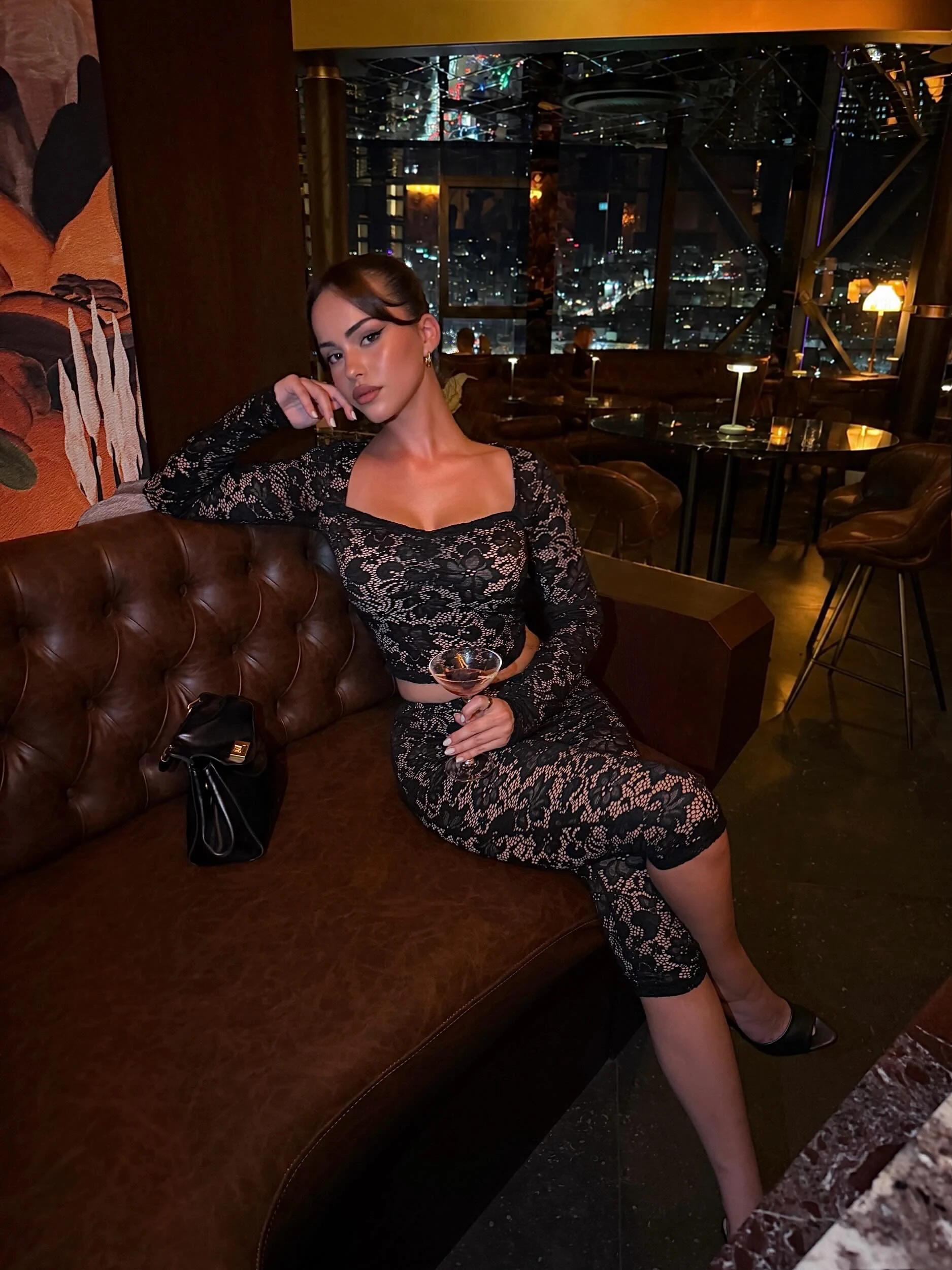 Fitted black lace long-sleeve top and midi skirt with dark underlayer and pointed-toe shoes.