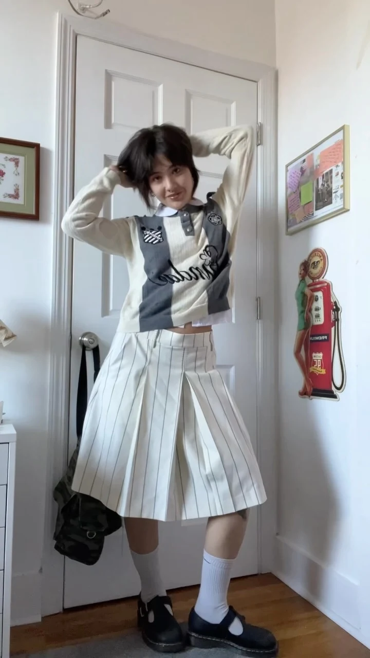 Color-blocked cropped sweater vest over a graphic shirt, pleated midi skirt, crew socks, and Mary Janes.