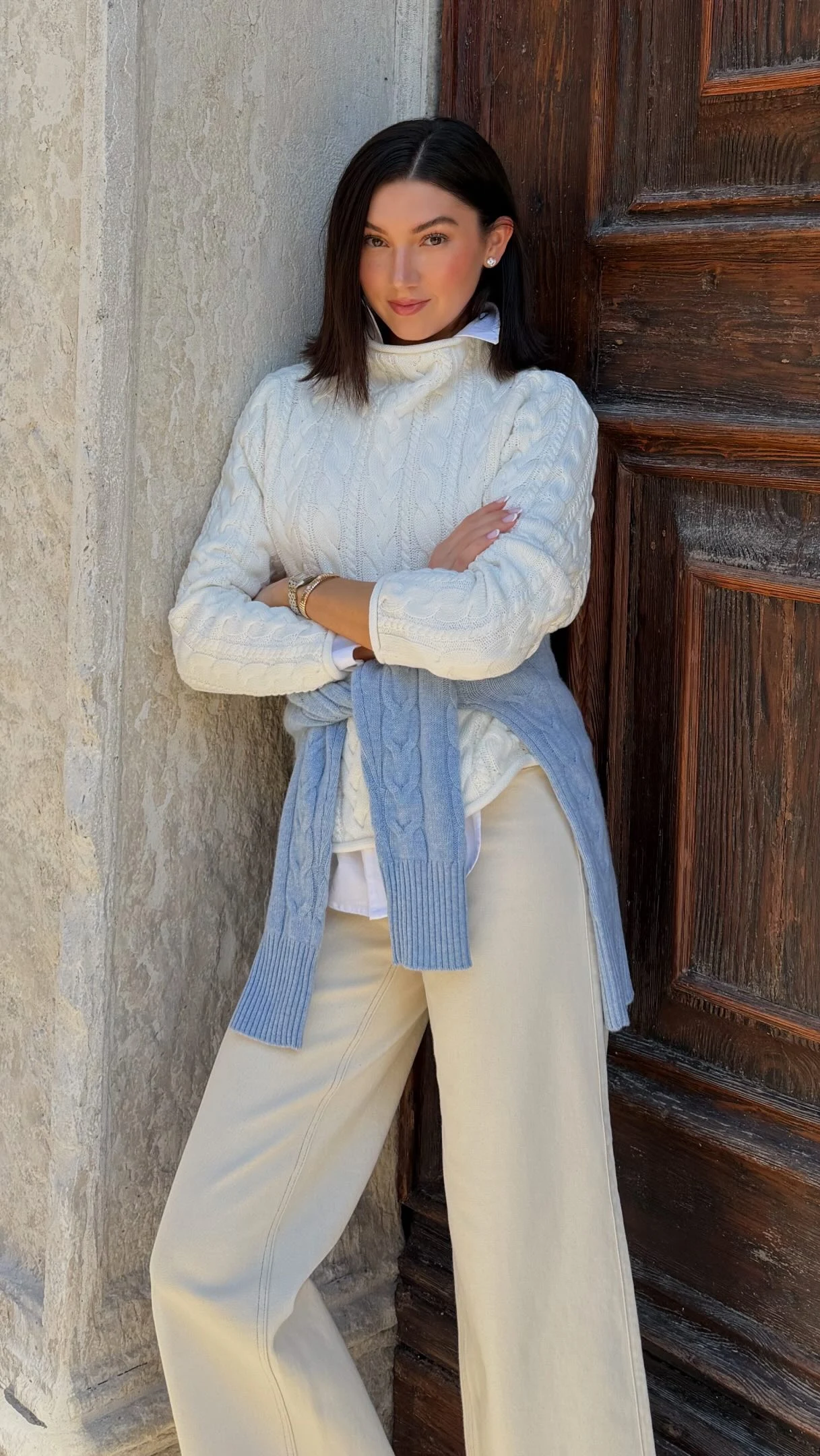 Cream cable knit turtleneck layered over a white button-down with matching cream wide-leg pants.