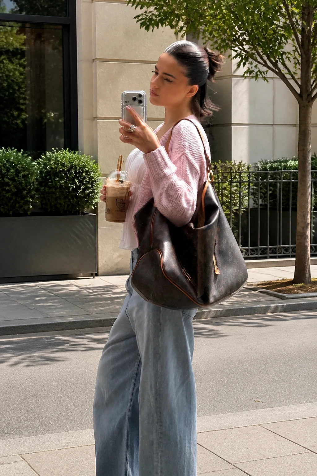 Light pink knit cardigan over a white camisole with wide-leg jeans and white sneakers.
