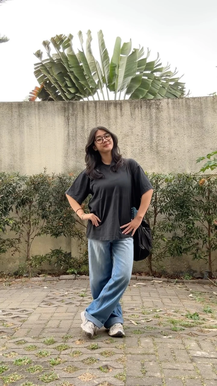 Oversized black tee, light-wash wide-leg jeans, chunky sneakers, and black shoulder bag for an easy casual look.