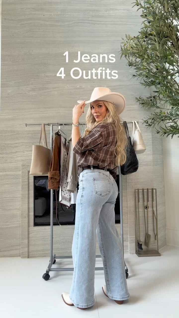 Person in brown plaid shirt, light-wash straight-leg jeans, and wide-brim hat near a clothing rack.